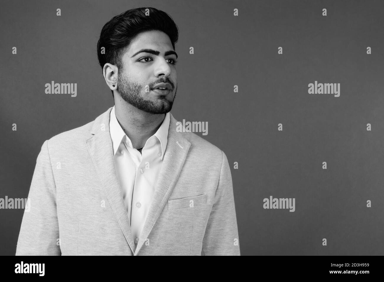 Young handsome bearded Indian businessman against gray background Stock Photo