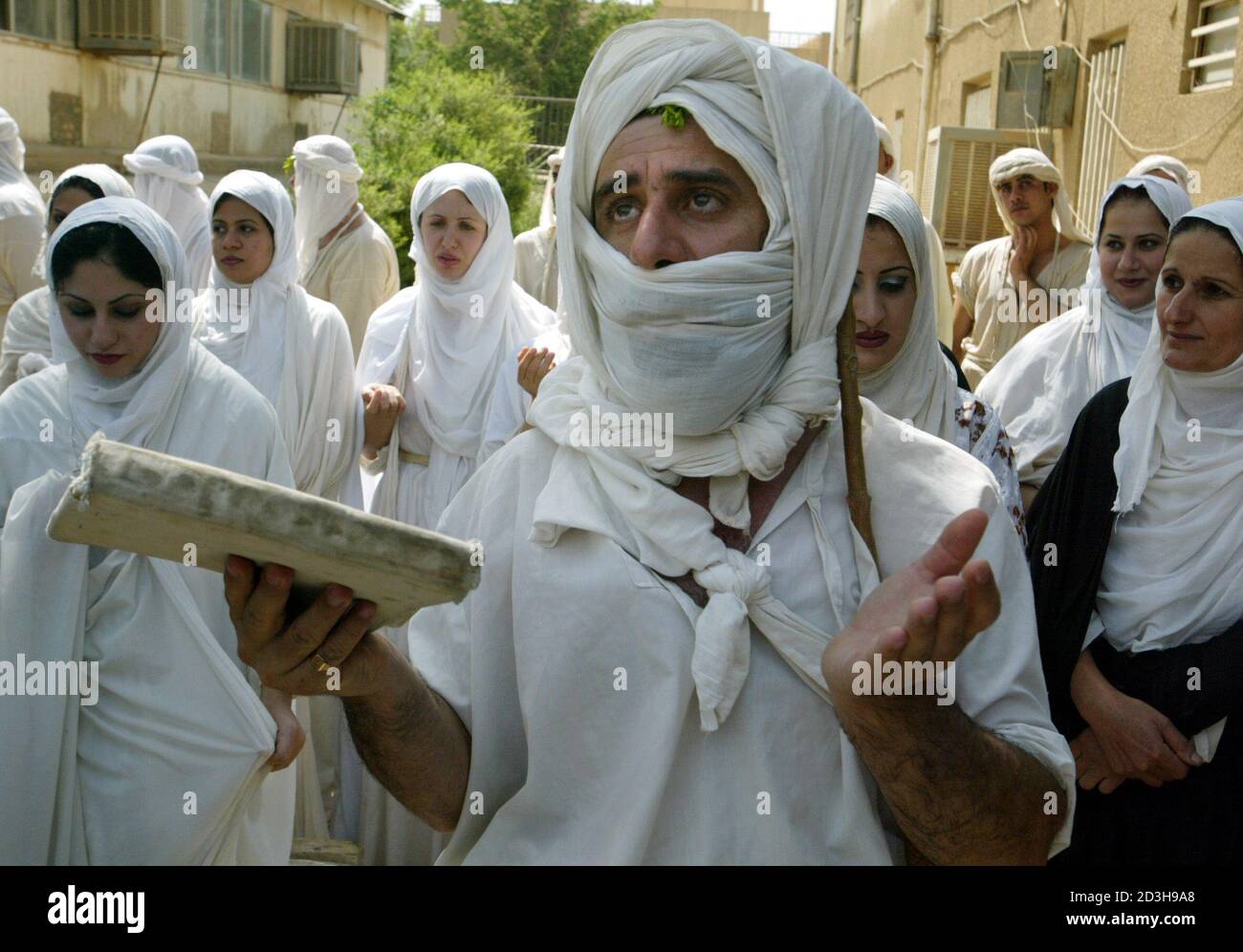 An Iraqi Mandean priest conducts a wedding ceremony for five couples in the ancient Aramaic language on the Tigris river in Baghdad June 8, 2003. Iraqi devotees of an obscure religion who take John the Baptist as their central figure perform virginity tests on their brides and take a dip in the murky Tigris river every Sunday to purify the soul.  Most of the world's 20,000 or so Mandeans live in southern Iraq and southwestern Iran. Stock Photo