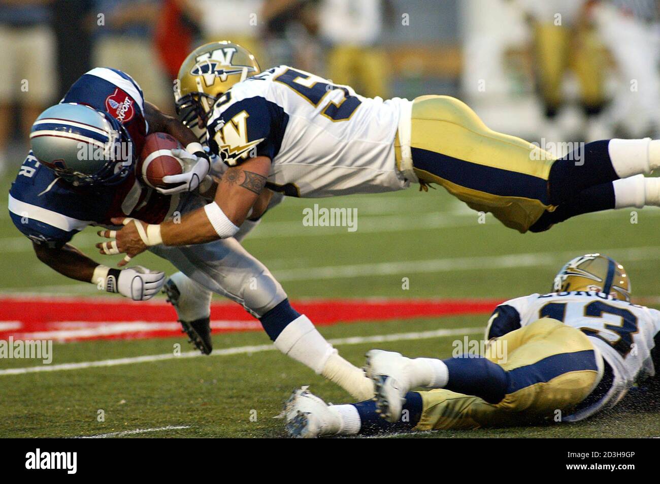 Montreal Alouettes running back Deonce Witaker (L) is tackled by Winnipeg  Blue Bomber's Ryland Wickman, during the first quarter of CFL action in  Montreal, July 29, 2003. Blue Bombers Tom Europe (13)