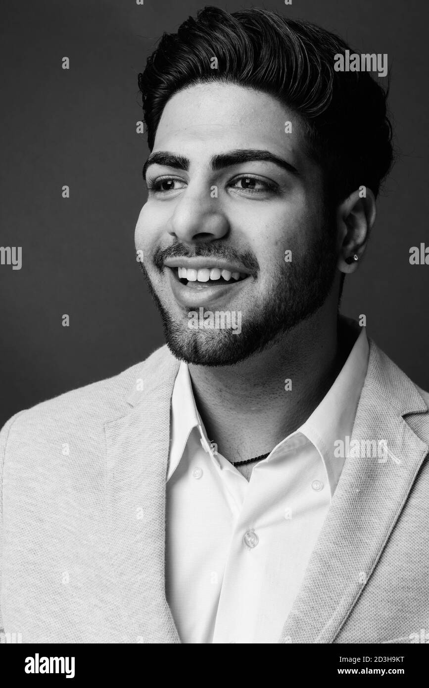 Young handsome bearded Indian businessman against gray background Stock Photo