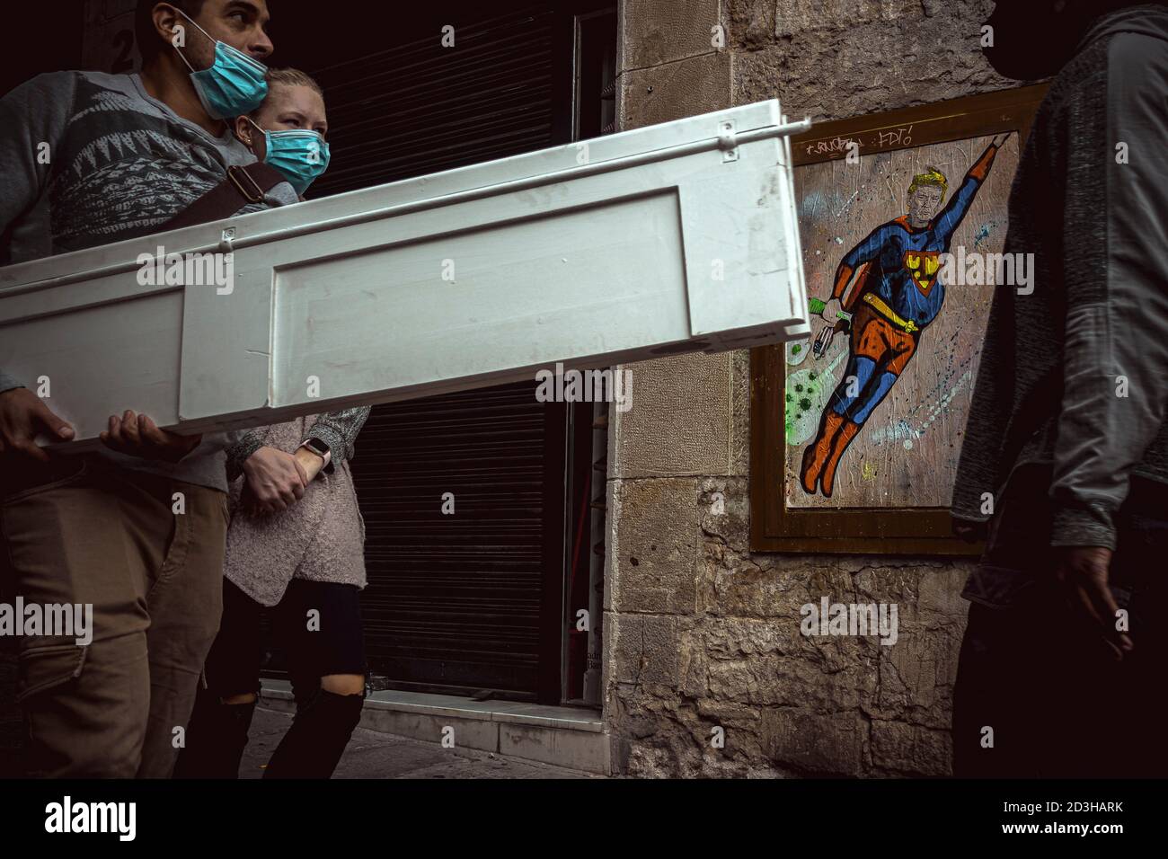 Barcelona, Spain. 8th Oct, 2020. Commuters pass a graffiti by Italian urban artist 'TVBoy', Salvatore Benintende, titled 'What doesn't kill you makes you stronger. Or not?' depicting US President Donald Trump wearing a Superman costume flying amid coronavirus clouds after his return to the white house while still suffering from the disease Credit: Matthias Oesterle/Alamy Live News Stock Photo