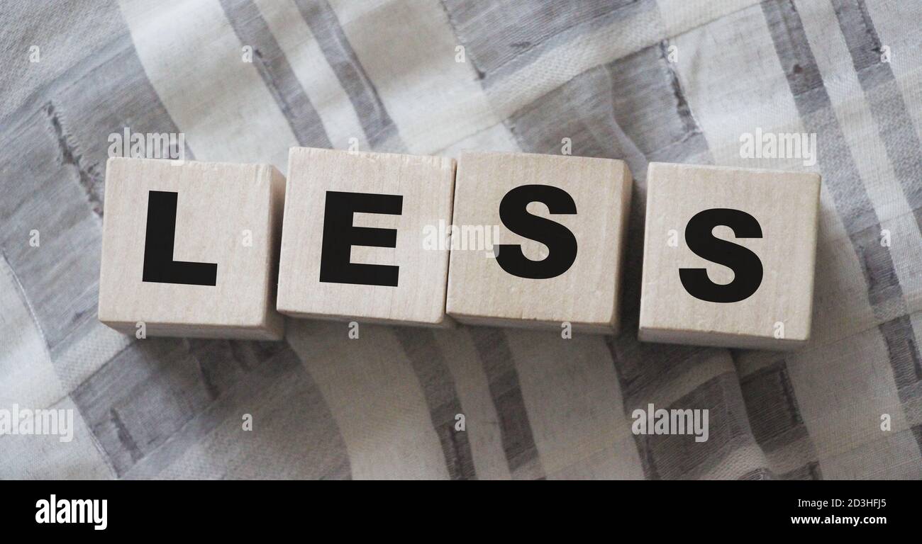 Less word on wooden cubic blocks with letters. Spend less or cut costs business concept Stock Photo