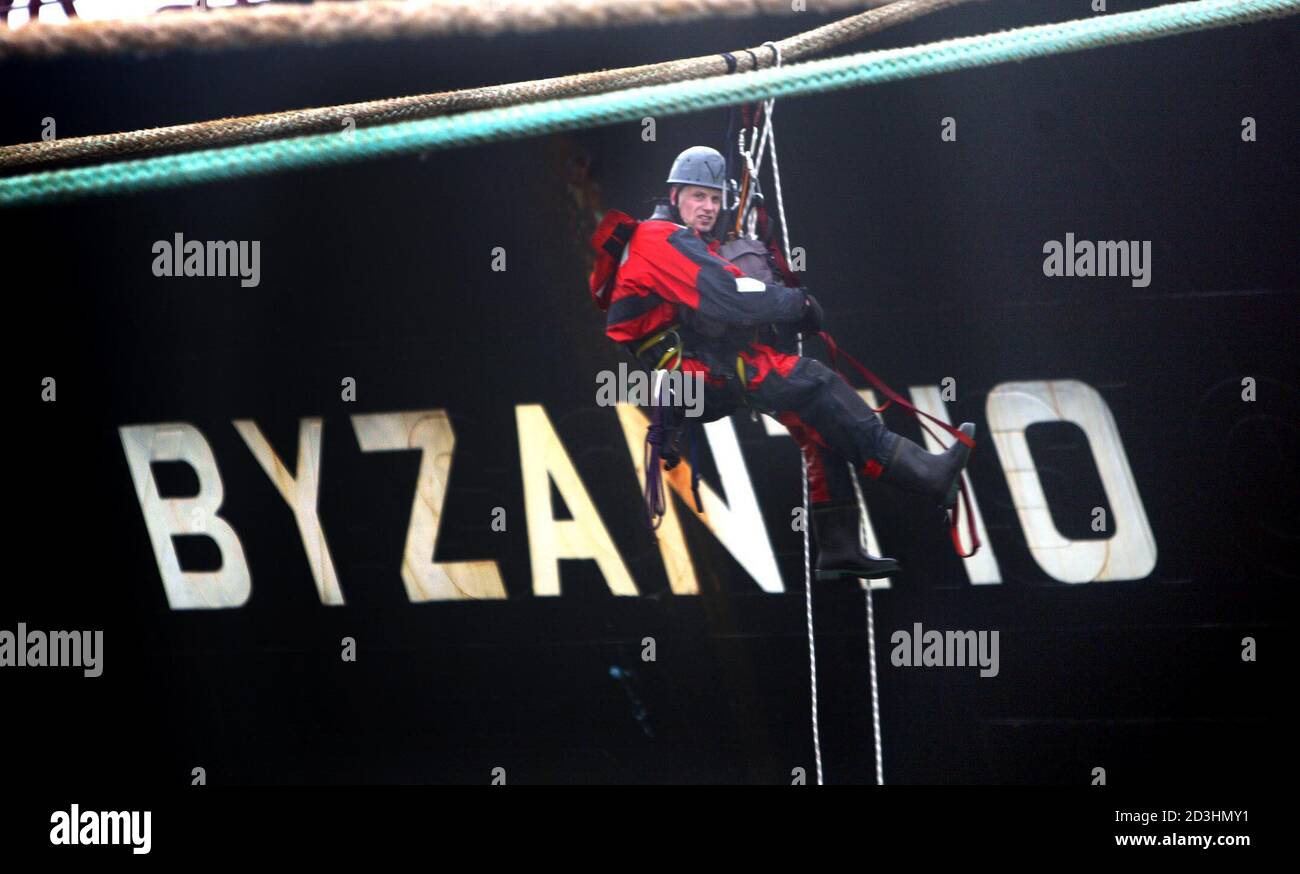A member of the environmental organisation Greenpeace hangs in climbing gear on the oil tanker Byzantio in the port of Rotterdam December 4, 2002. The ageing oiltanker is under fire from environmentalists who claims it is posing an oil-spill threat following the disaster of the [Prestige] oil tanker which broke apart at sea off the [Spanish] coast two weeks ago. Stock Photo