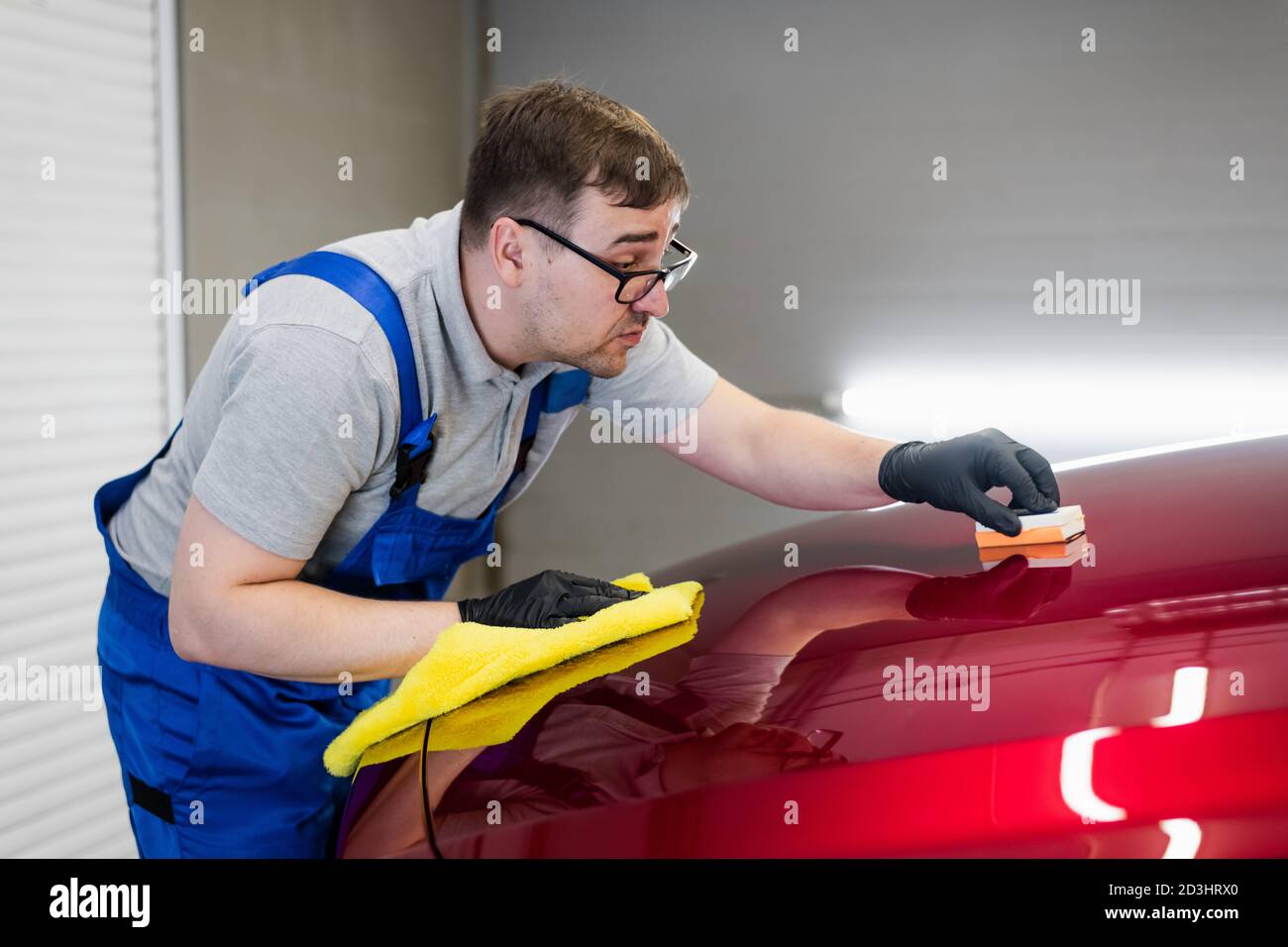 Man worker of car detailing studio applying ceramic coating on car