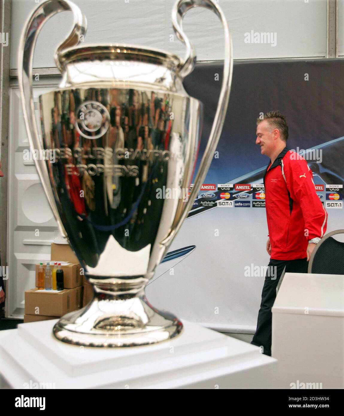 French coach of soccer team AS Monaco Didier Deschamps (R) passes behind  the UEFA Champions League trophy after a news conference at the Arena  stadium in Gelsenkirchen, May 25, 2004. AS Monaco