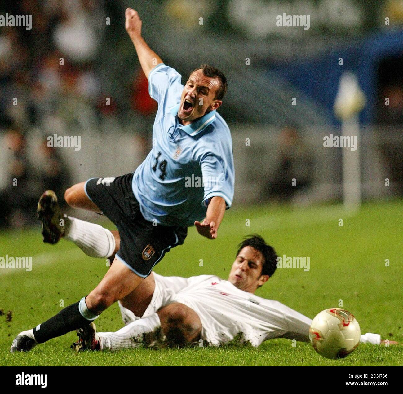 Uruguay's Julio Rodriguez (L) is tackled by Iran's Hamed Kavianpour during  their Carlsberg Cup final in Hong Kong February 4, 2003. Uruguay beat Iran  5-3 in the penalty shootout after the 120