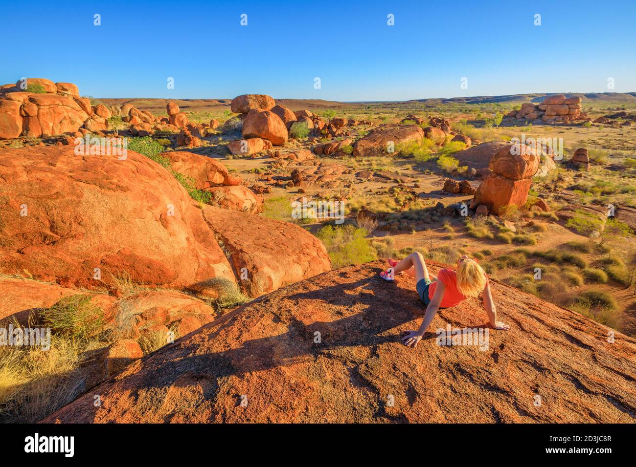 Outback, Northern Territory, Australia. Tourist woman rests after the trek to the top view of Karlu Karlu Devils Marbles. Traveler looking panorama Stock Photo