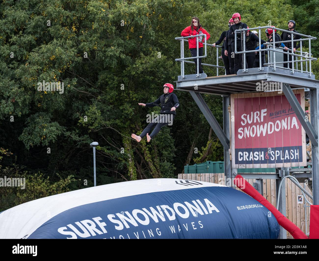 An adventurous lady leaps from a high platform to bounce on the airbag at Surf Snowdonia, Wales Stock Photo