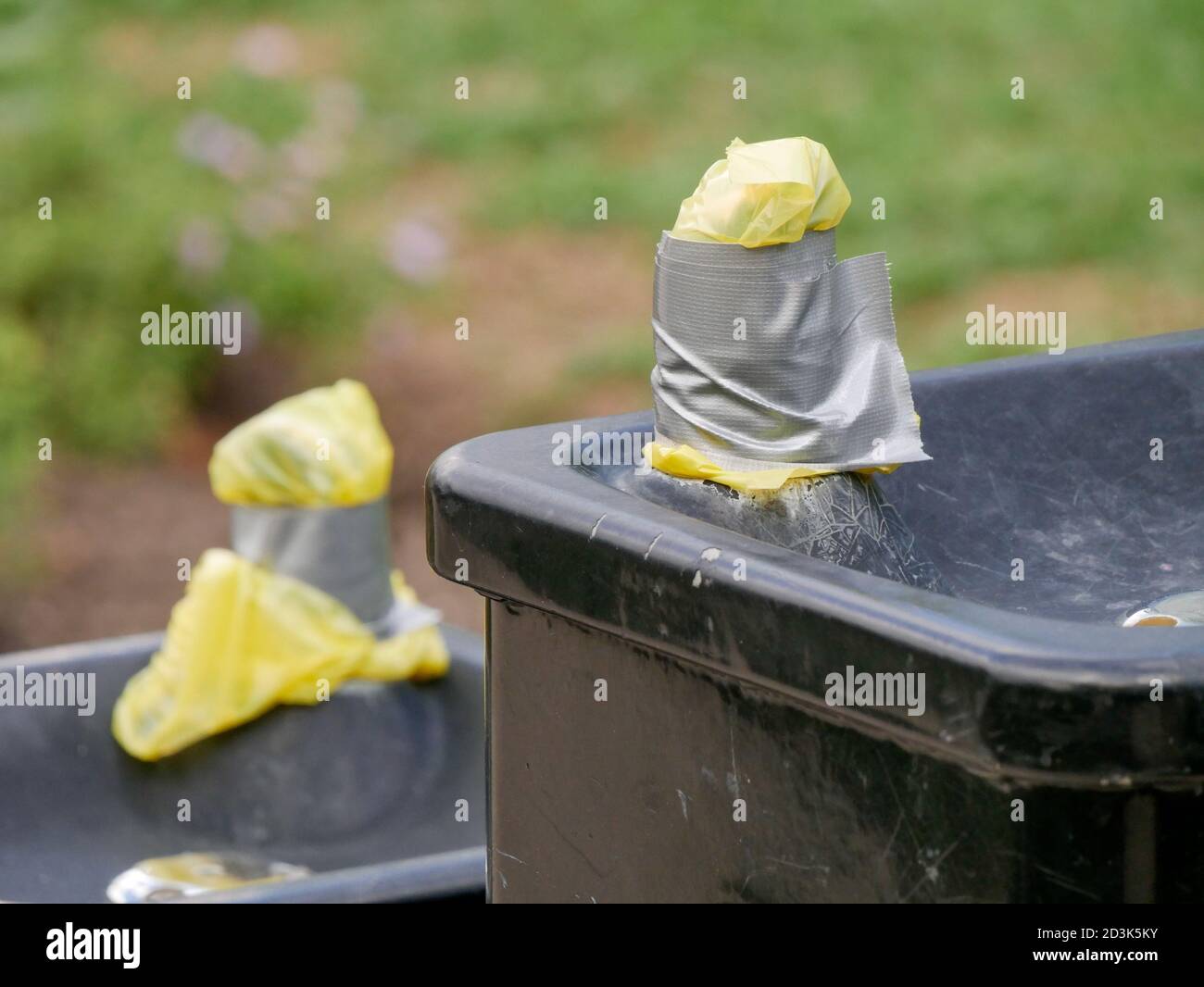 Public drinking fountain turned off with spigots covered by plastic and tape during COVID-19 pandemic. Stock Photo
