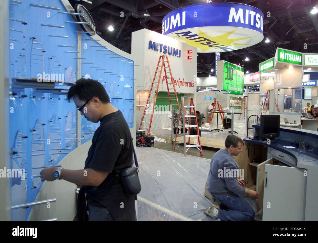 Belkin Designer James Chu L Works Along With A Technician As They Put The Finishing Touches On One Of The Hundreds Of Displays At Comdex 01 In Las Vegas November 11 01