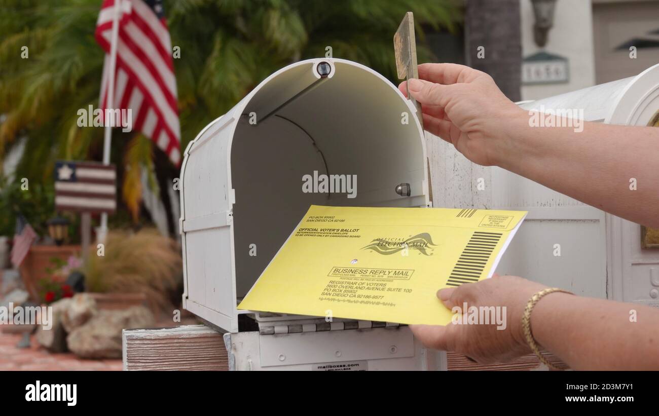 American mailbox with flags, older woman's hands returning mail-in election ballot. Illustrative editorial taken in Vista, CA / USA on October 8, 2020 Stock Photo