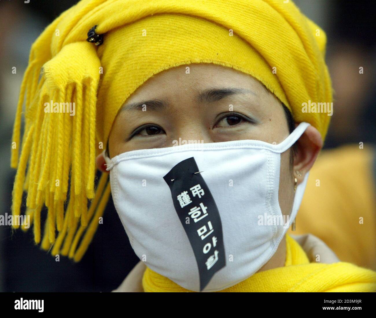 A South Korean protester wears a mask pinned with a funeral ribbon symbolising a criticism of the two opposition parties during a pro-president rally near parliament in Seoul March 10, 2004. South Korea's main opposition parties prolonged the political agony on Wednesday by putting off an unprecedented attempt to impeach President Roh for at least another day. The funeral ribbon reads:' Offering our condolence to an unprincipled coalition between the Grand National Party and the Millennium Democratic Party'. REUTERS/Lee Jae-Won  LJW/FA Stock Photo