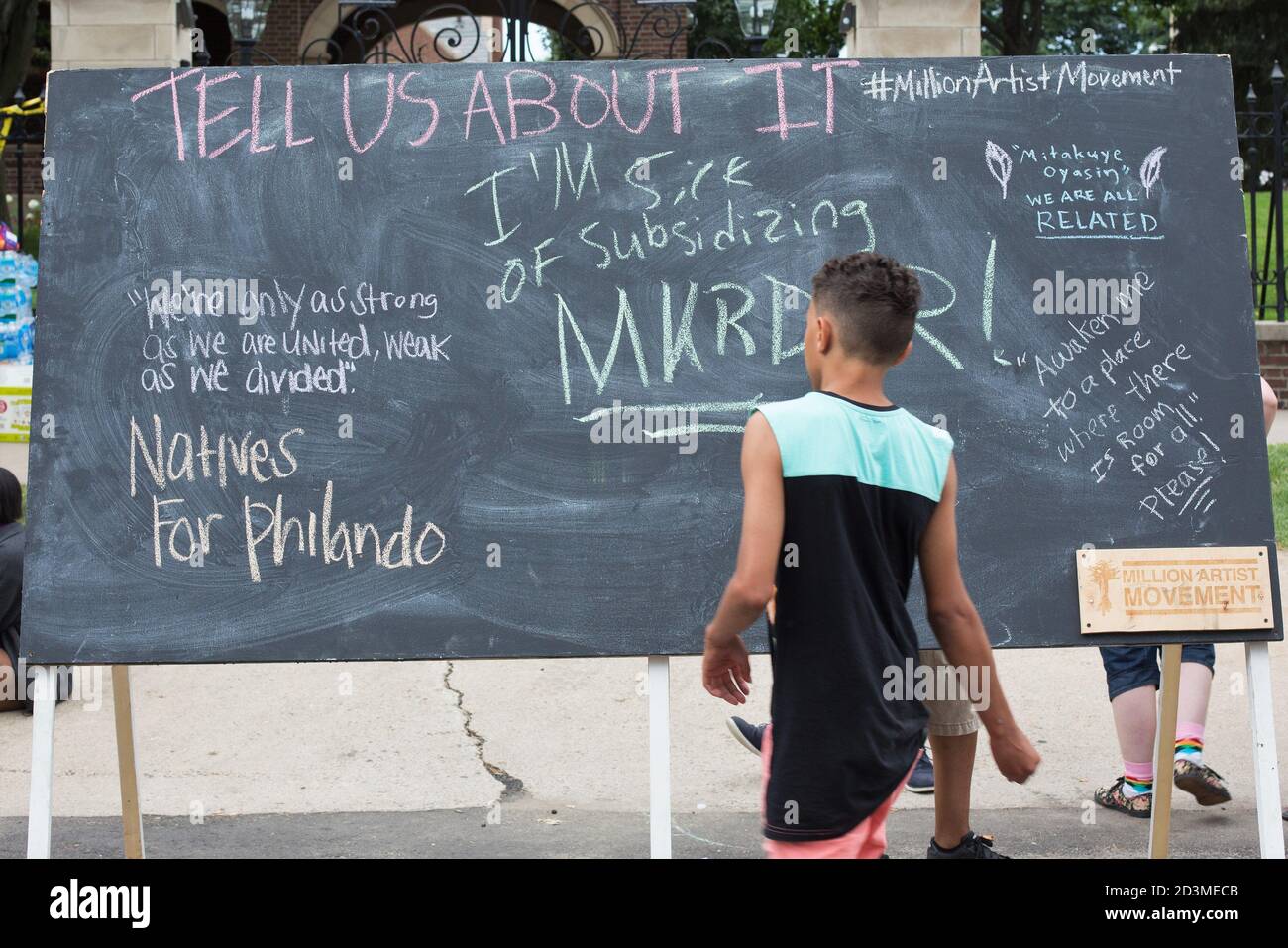 A teen boy looks at a chalk board with messages outside the MN Governor's residence during a protest over the killing of Philando Castile by police. Stock Photo