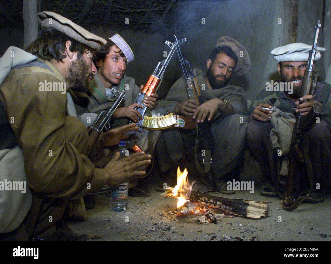 Anti-Taliban Afghan fighters huddle around a fire to get warm in the Tora  Bora mountains December 15, 2001. Afghan fighters whittled away at Osama  bin Laden&#39;s remaining guerilla forces on Saturday, capturing
