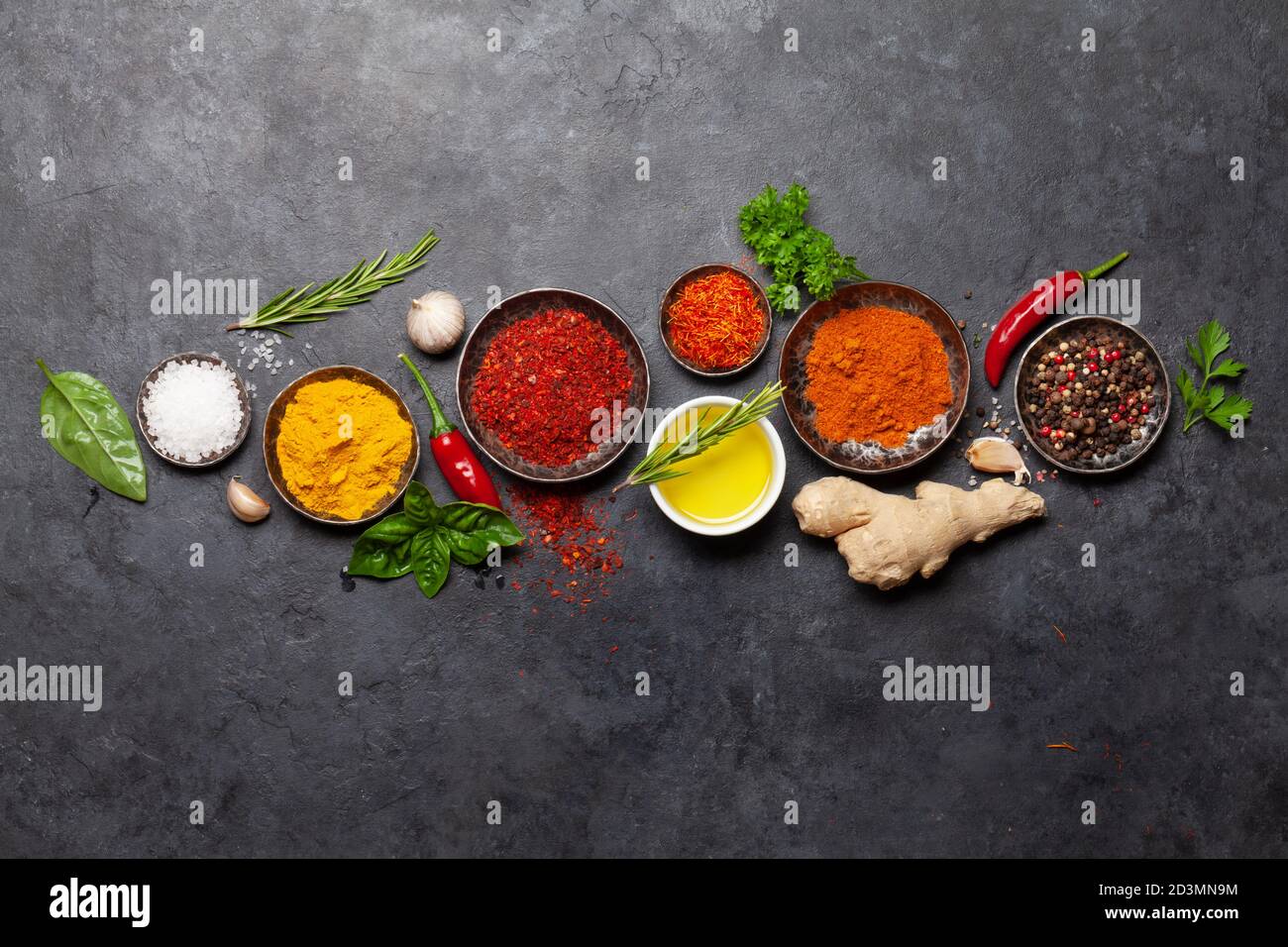 Various spices, herbs and condiments on dark stone table. Indian cuisine. Top view flat lay with