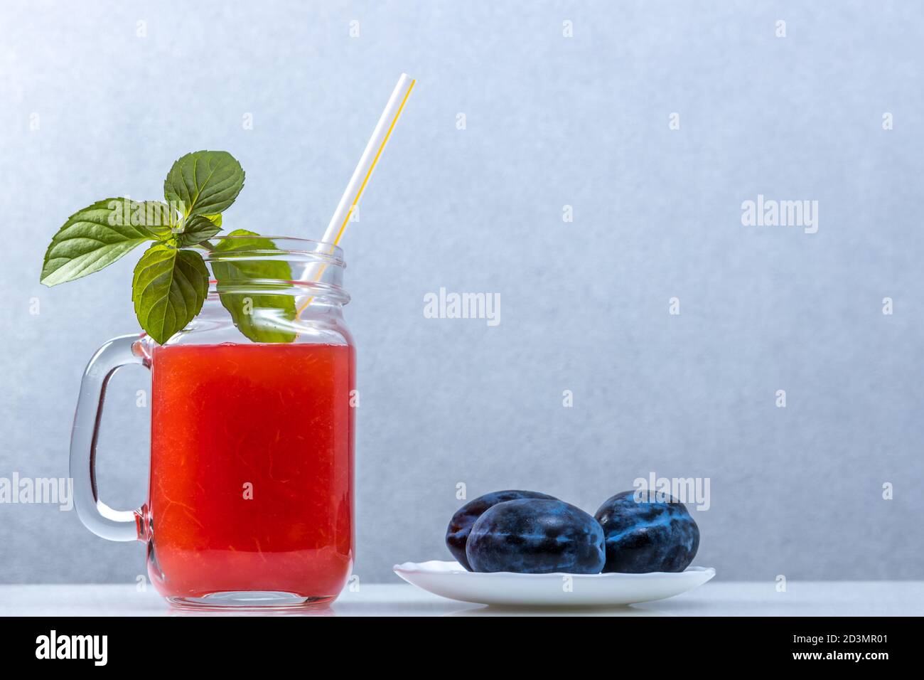 Watermelon smoothie in a jar with mint leaves and prunes, with a cocktail straw Stock Photo