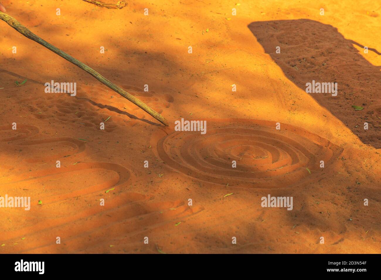 Kings Creek Station, Northern Territory, Australia - Aug 21, 2019: aboriginal people creating shapes with red sand on the ground in aboriginal art Stock Photo