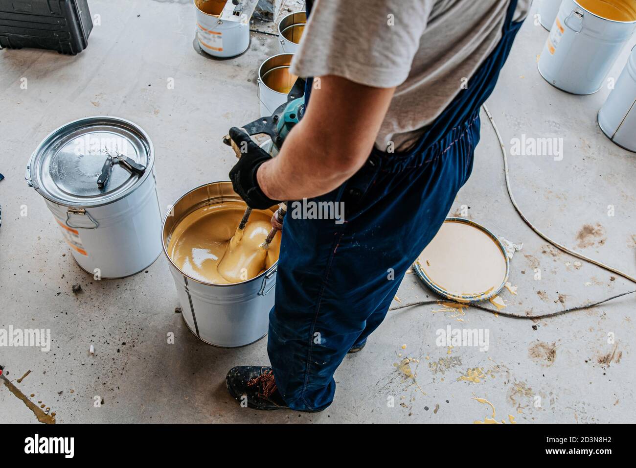 Worker mixing yellow epoxy resin with the mixer in a tin bucket Stock