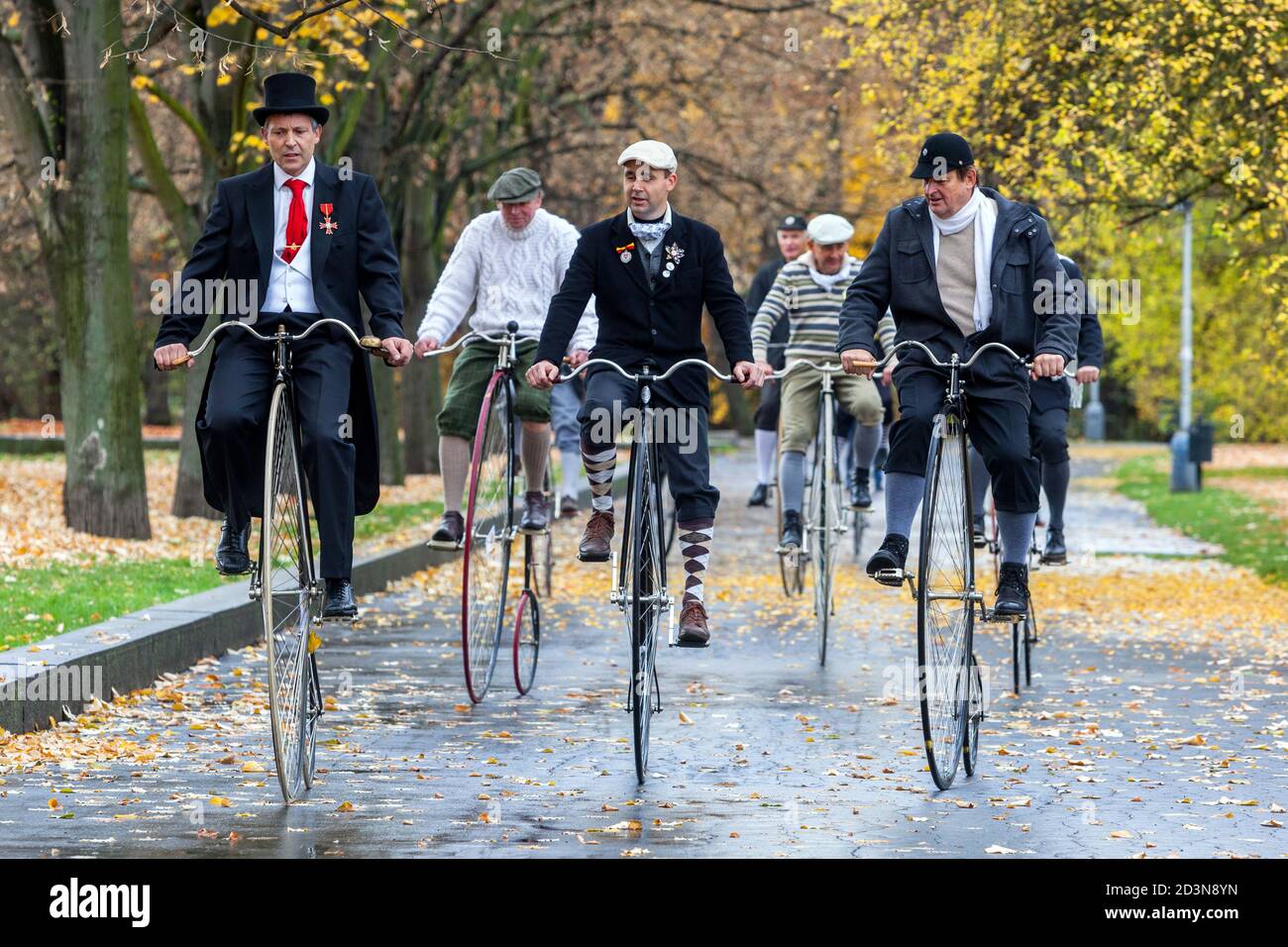 Group of gentlemen on Penny Farthing bicycles high wheels Men group ride in park Stock Photo