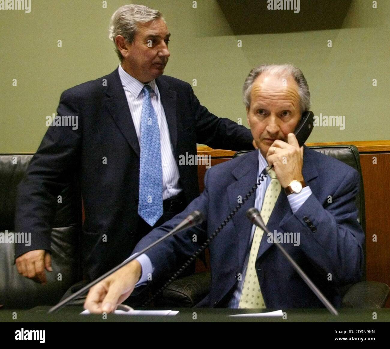 Juan Maria Atutxa, president of Basque parliament, talks on a telephone beside Basque Nationalists Party (PNV) deputy Jose Antonio Rubalkaba at the Basque parliament in Vitoria June 20, 2003. Spain's public prosecutor ordered Basque courts to open a criminal investigation into the leaders of the regional parliament for defying a Supreme Court order to dissolve a party linked to ETA. REUTERS/Vincent West  SP/WS Stock Photo
