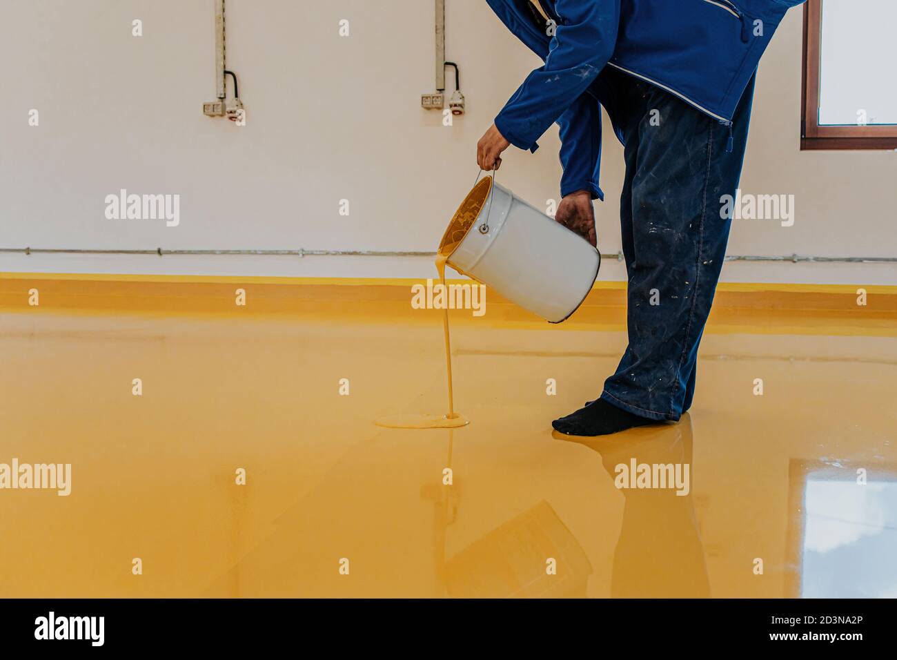 Worker, coating floor with selfleveling epoxy resin in industrial