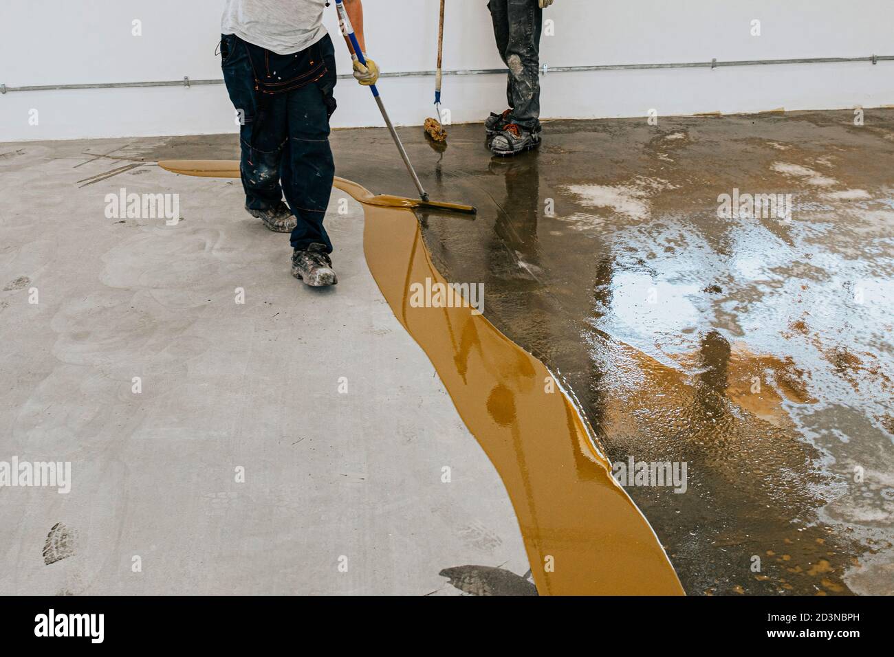 A worker applies the primer to the concrete floor.Epoxy resin project