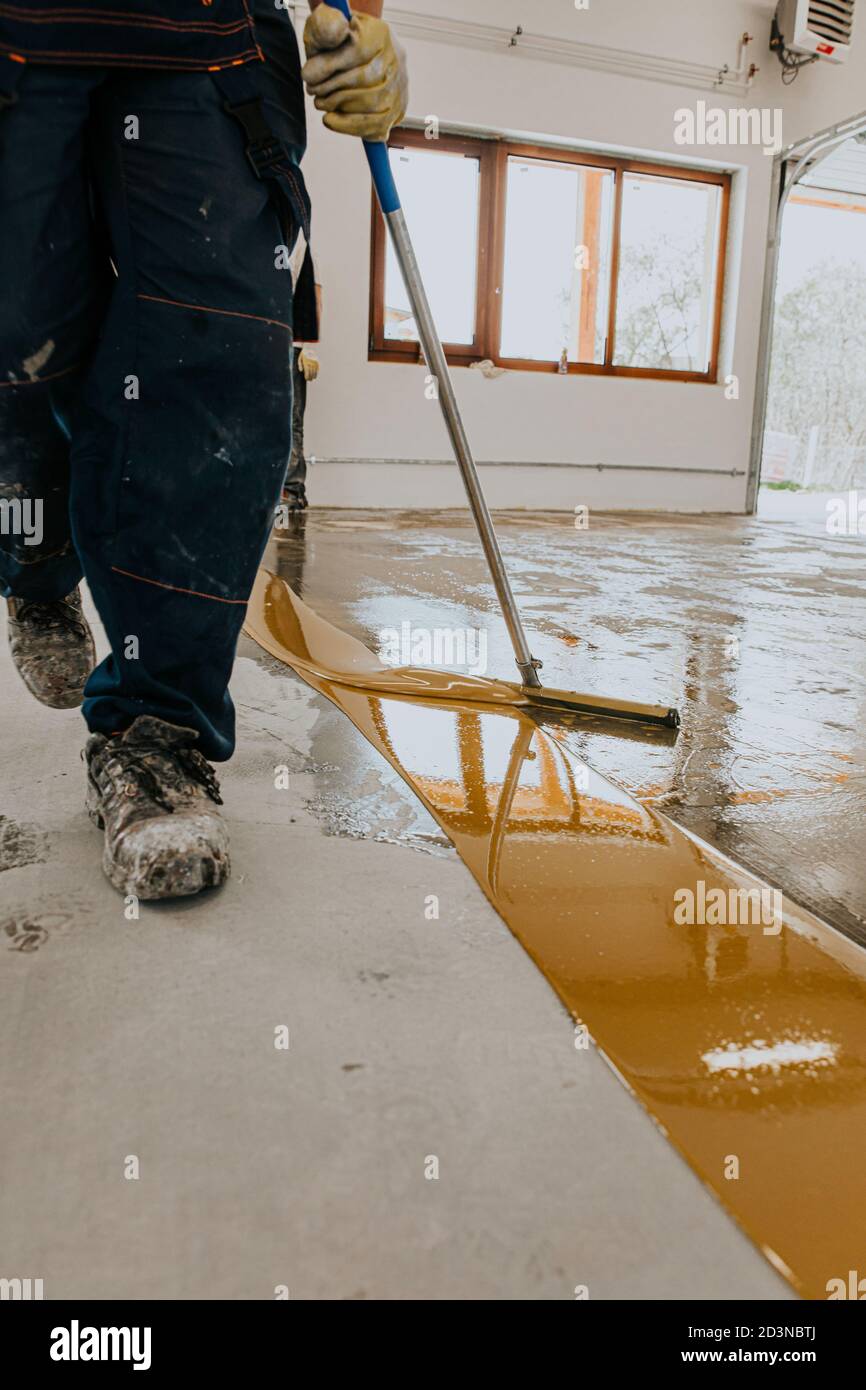 A worker applies the primer to the concrete floor.Epoxy resin project