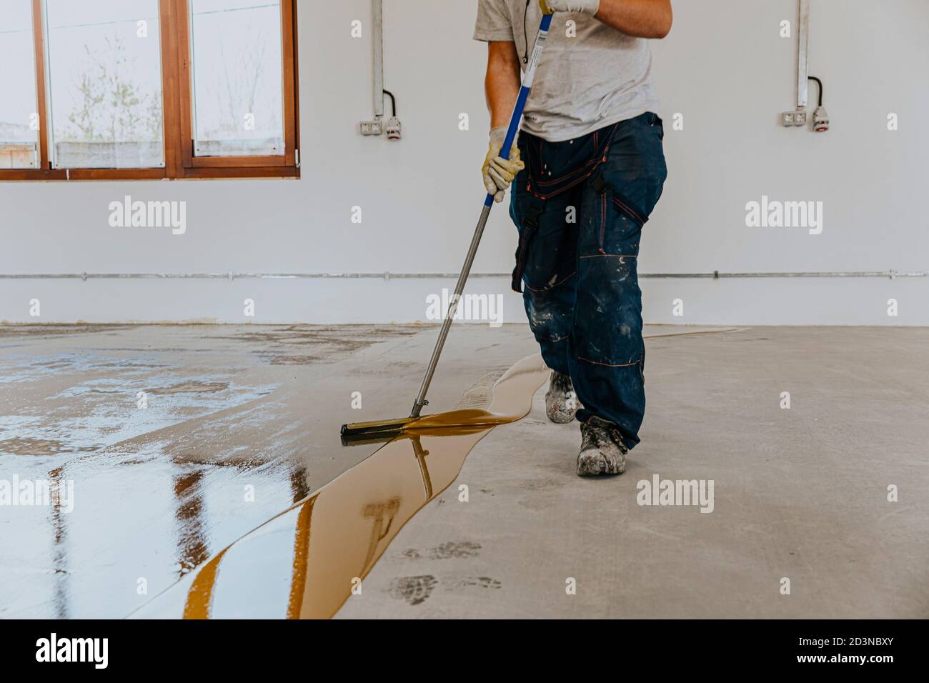 A worker applies the primer to the concrete floor.Epoxy resin project