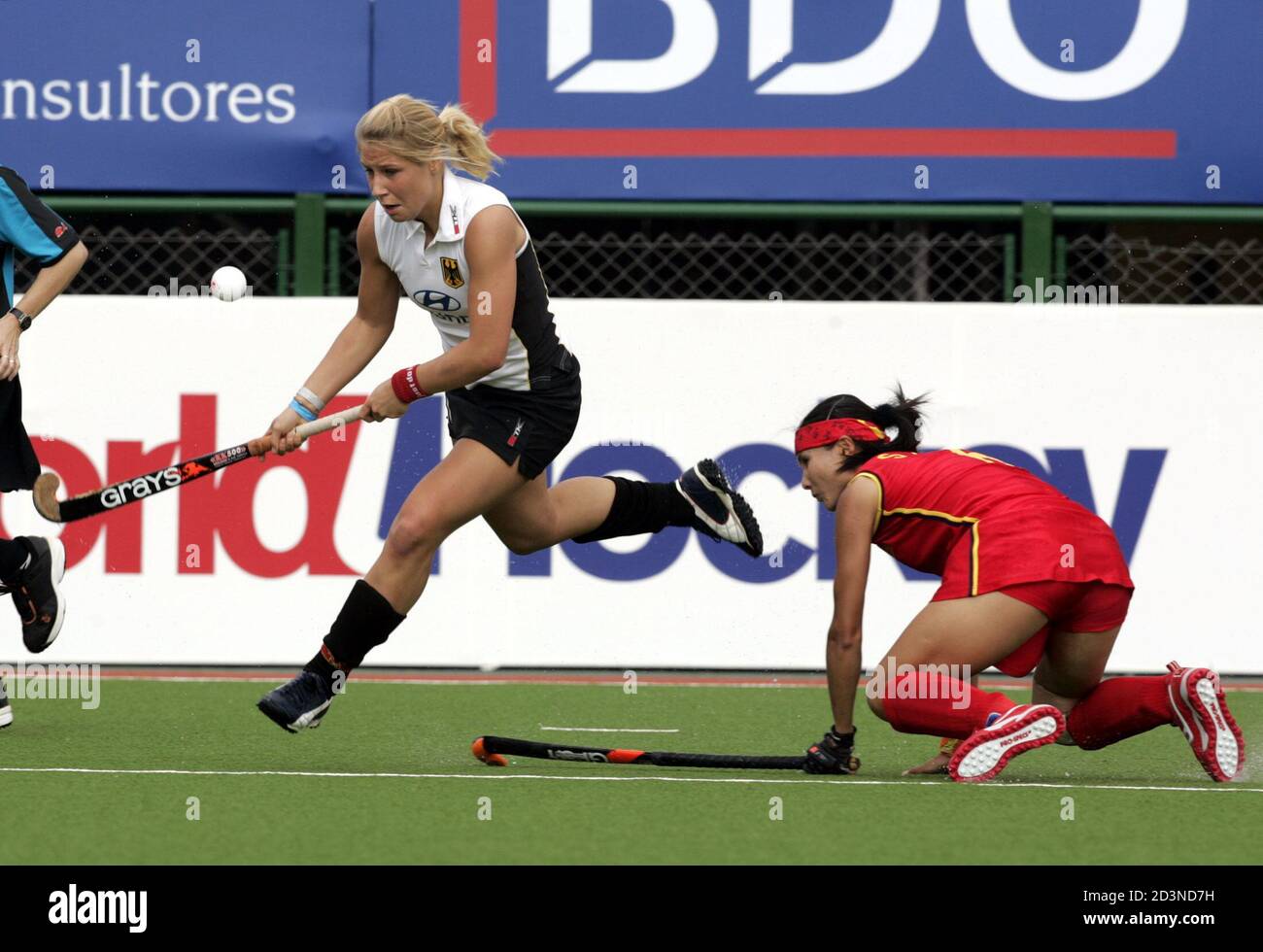 Kerstin Hoyer (L) of Germany hits the ball away as China's Mai Shaoyan  falls to the ground, during their women's field hockey Champions Trophy  match, played at the Jockey Club in the