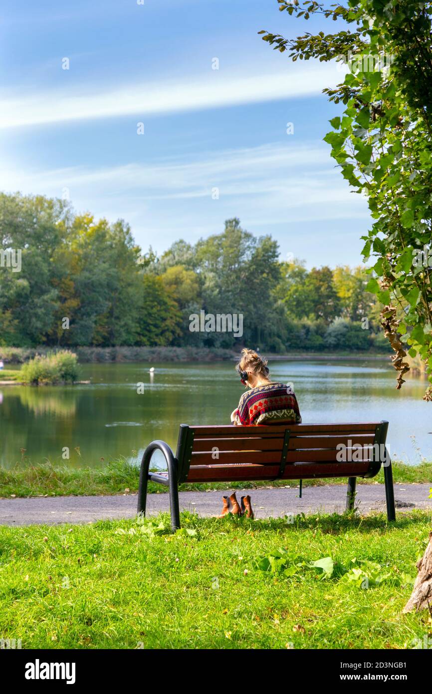 Woman sitting on a park bench hi-res stock photography and images - Alamy