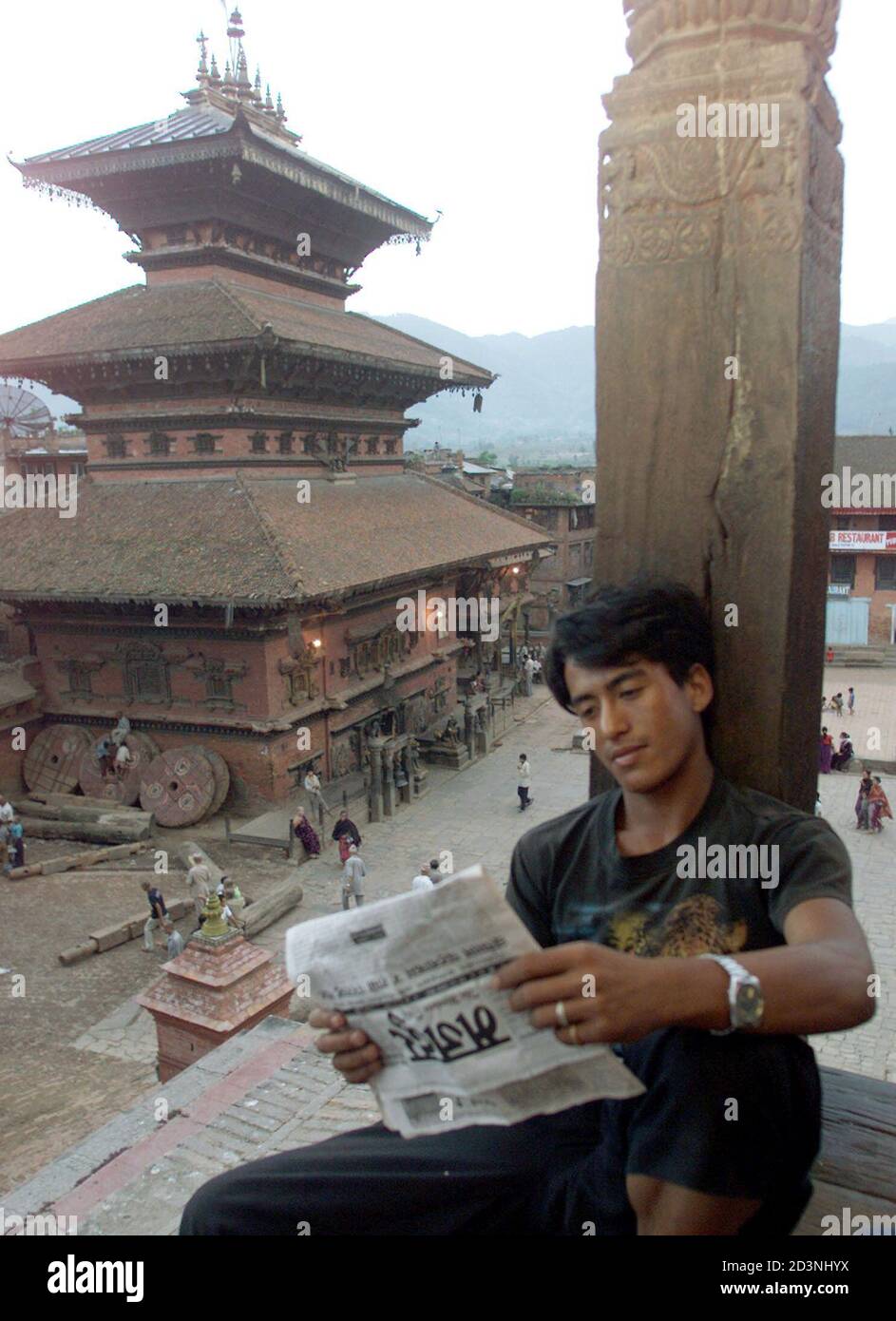 Nepalese Man Reads The Newspaper While Sitting On Top Of A Temple In Bhaktapur Some 15 Km From 