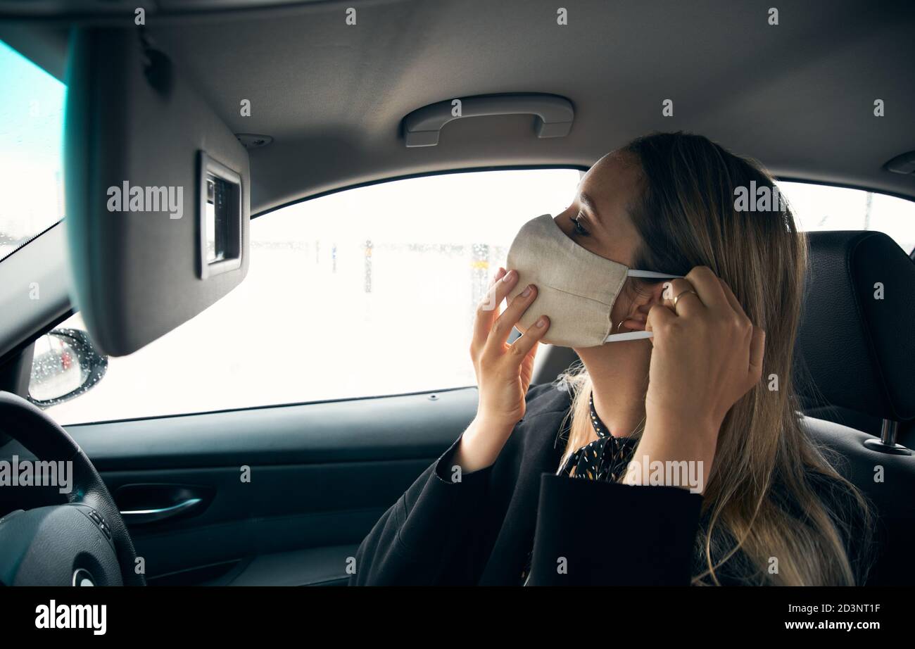 Young Businesswoman Putting On Face Mask In Car Before Going Into Work In Office Stock Photo
