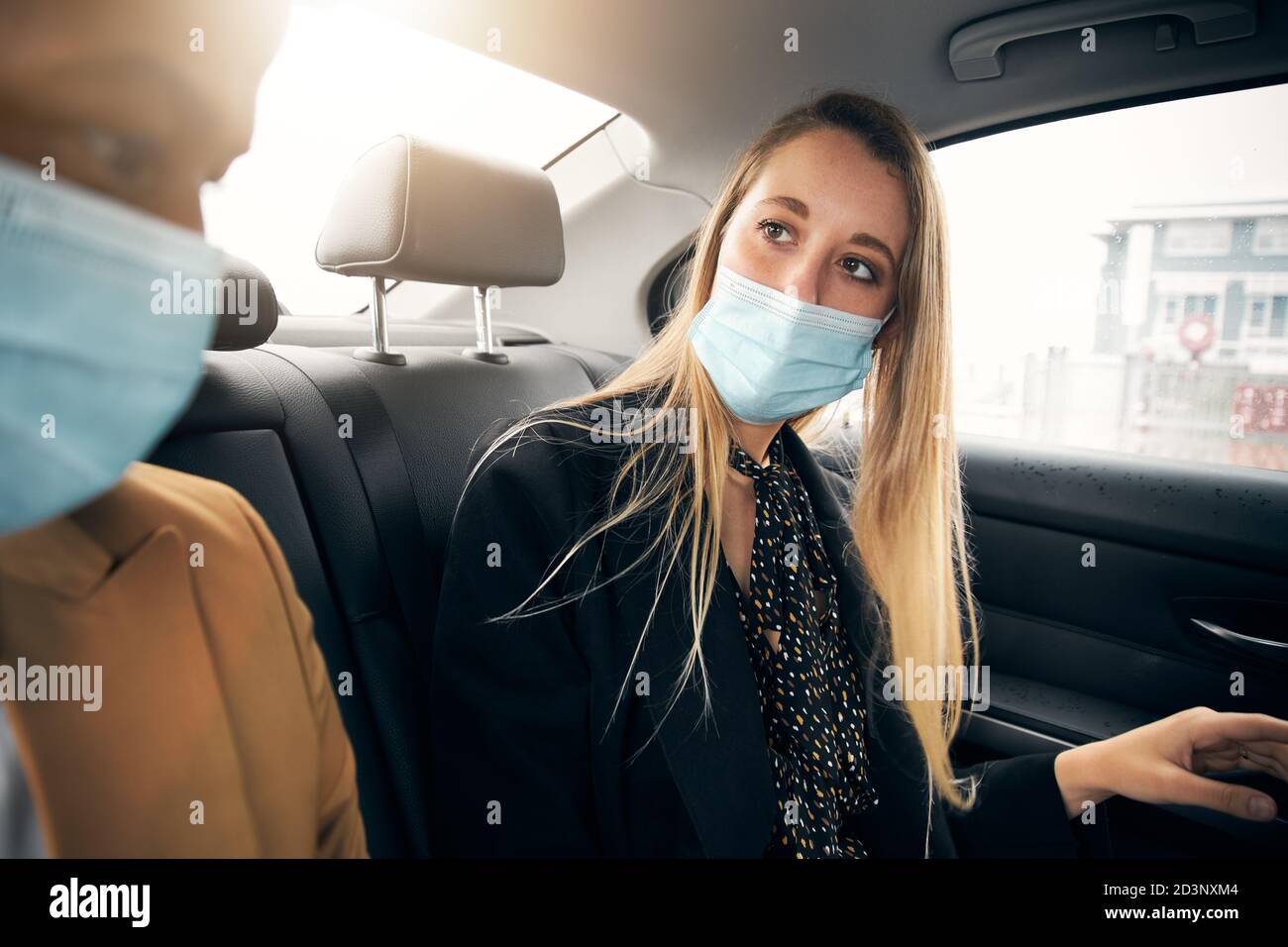 Business Couple Wearing Masks Having Conversation In Back Of Taxi During Health Pandemic Stock Photo