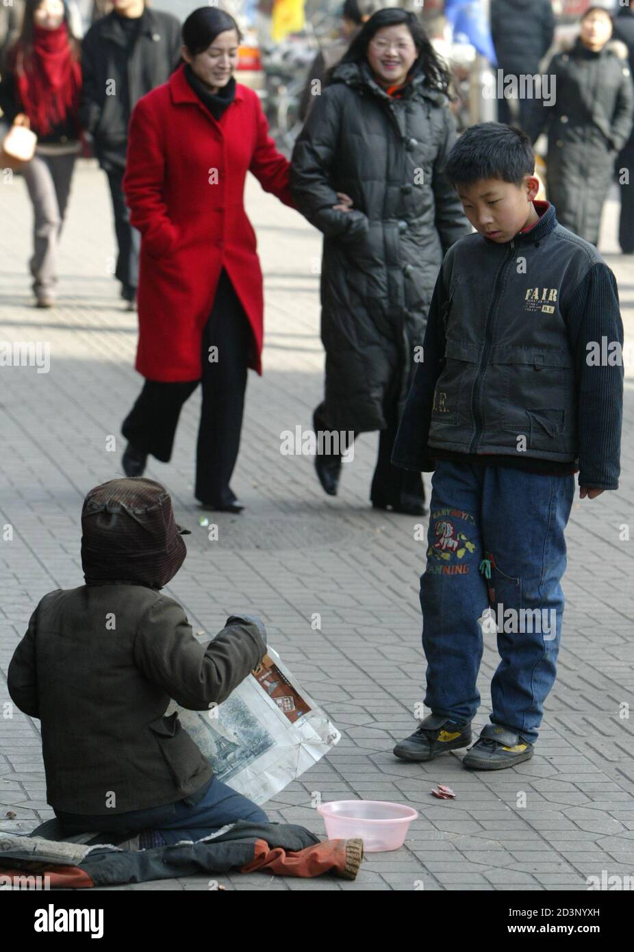 A boy (R) stares at a child begger sitting on the pavement in Taiyuan, the capital of Shanxi Province January 29, 2005. China cut the number of poverty-sticken people by three million in 2004, an official newspaper said this month, as the country grapples with a yawning gap between the rich and the poor. REUTERS/Alfred Cheng Jin  ALF/AA Stock Photo