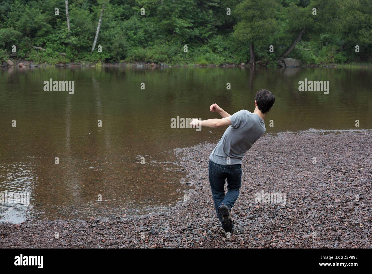 A young man skipping a rock into a lake Stock Photo Alamy