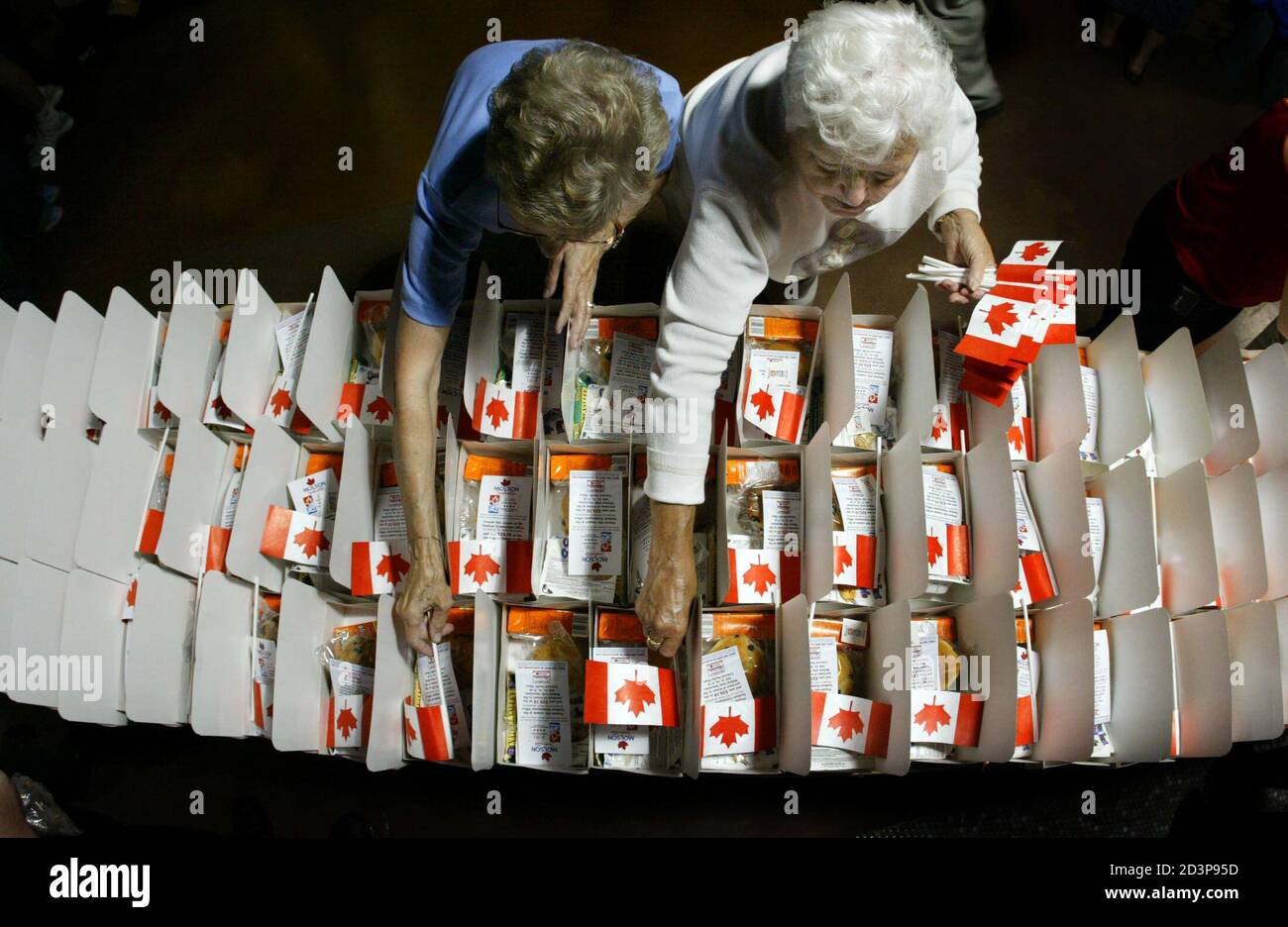 Volunteers place Canadian flags in lunch boxes, in Vancouver June 30, 2003, while preparing for the upcoming 2010 Olympic Bid annoucement. The boxes will be handed out to 18,000 people who will gather in GM Place to watch the announcement from Prague on July 2. Vancouver is competing with Salzburg, Austria and Pyeongchang, South Korea to host the 2010 Winter Olympics. REUTERS/Andy Clark  AC/GAC Stock Photo