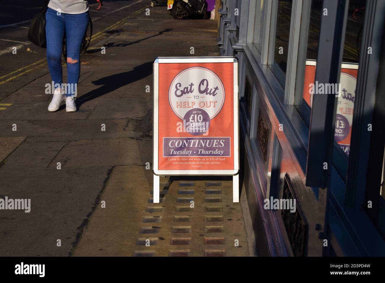 A person walks past an Eat Out To Help Out street sign in Central London Stock Photo