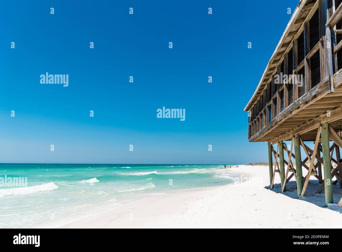 An old wooden beach house next to a clear blue ocean and white sand beach on Shell Island, Panama City, Florida Stock Photo