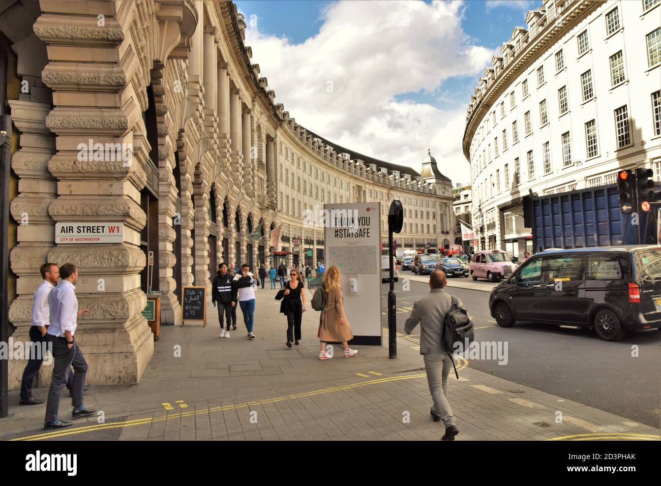 People walking past a Stay Safe social distancing street sign and hand sanitiser dispenser on Regent Street, London, 2020. Stock Photo
