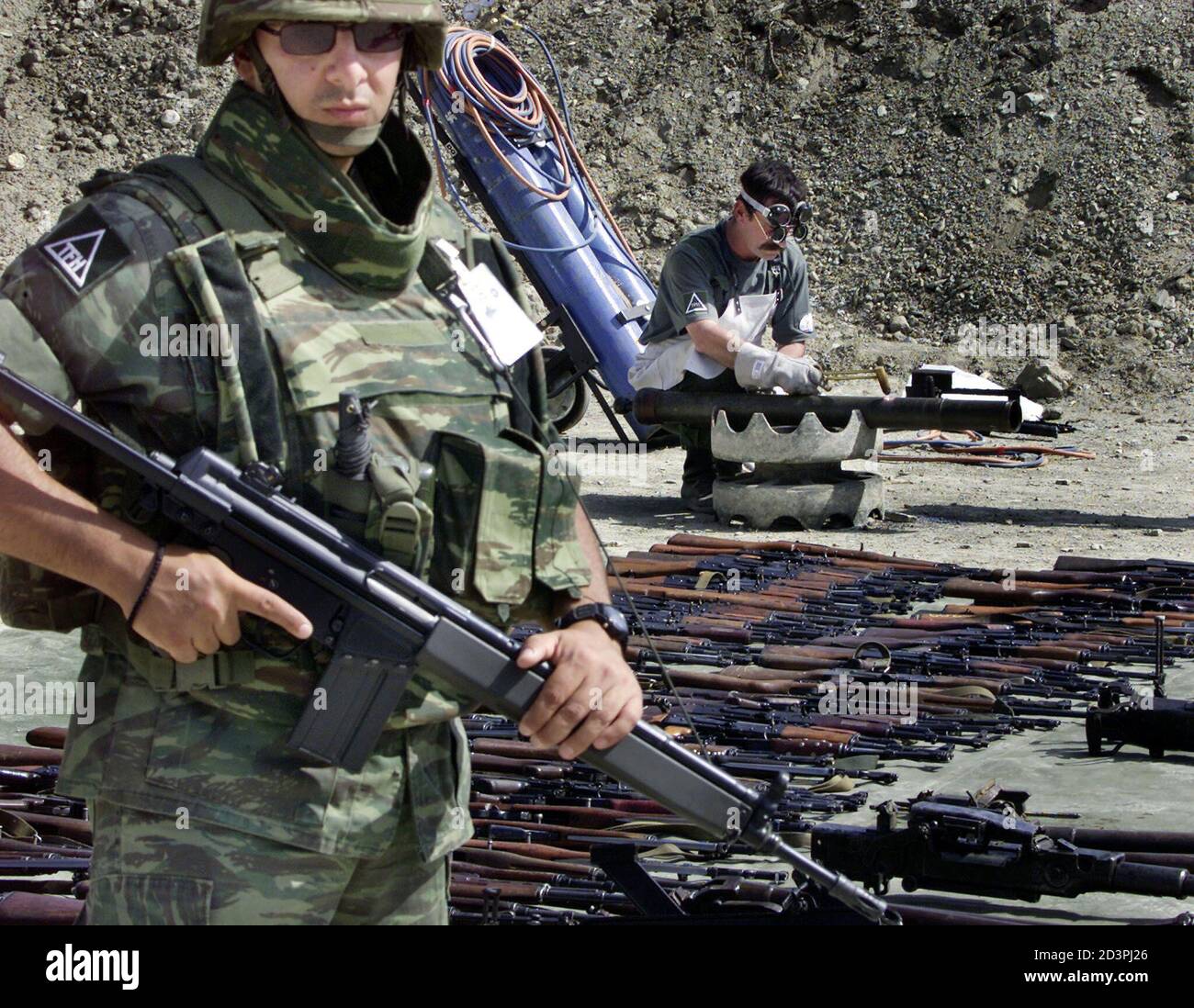 Greek Soldier Stands Guard As Hungarian Engineer Destroys Weapons Collected  From Albanian Fighters At The Macedonian Army Base In Krivolak September  10, 2001. Macedonia May Bow To International Pressure And Accept A