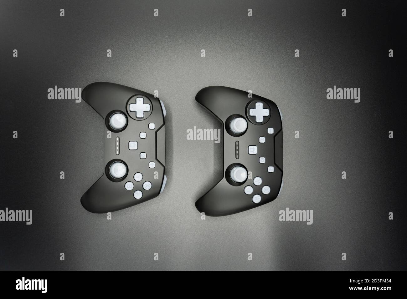 Two black game joysticks with white buttons isolated on gray background ...