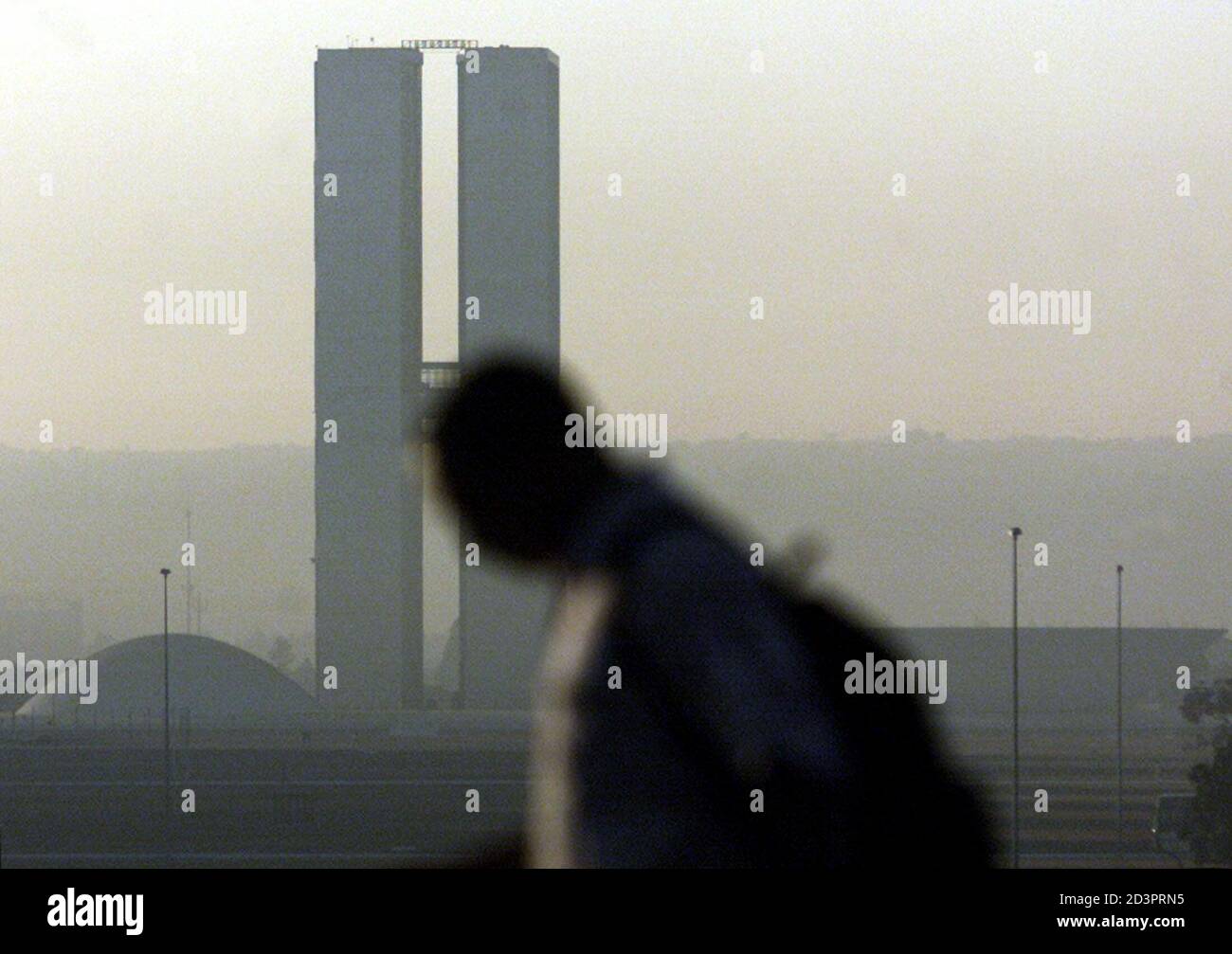 A pedestrian walks near the Congress building, enveloped in a haze, in Brasilia early June 24, 2003. The dry season, which runs from April through September in Brazil's central west region, has brought extremely low humidity levels of between 15 and 30 percent. Wildfires are common throughout the region, a savannah-like area with vegetation composed of open pasture and sparce trees, during the period. REUTERS/Jamil Bittar  JB/GN Stock Photo