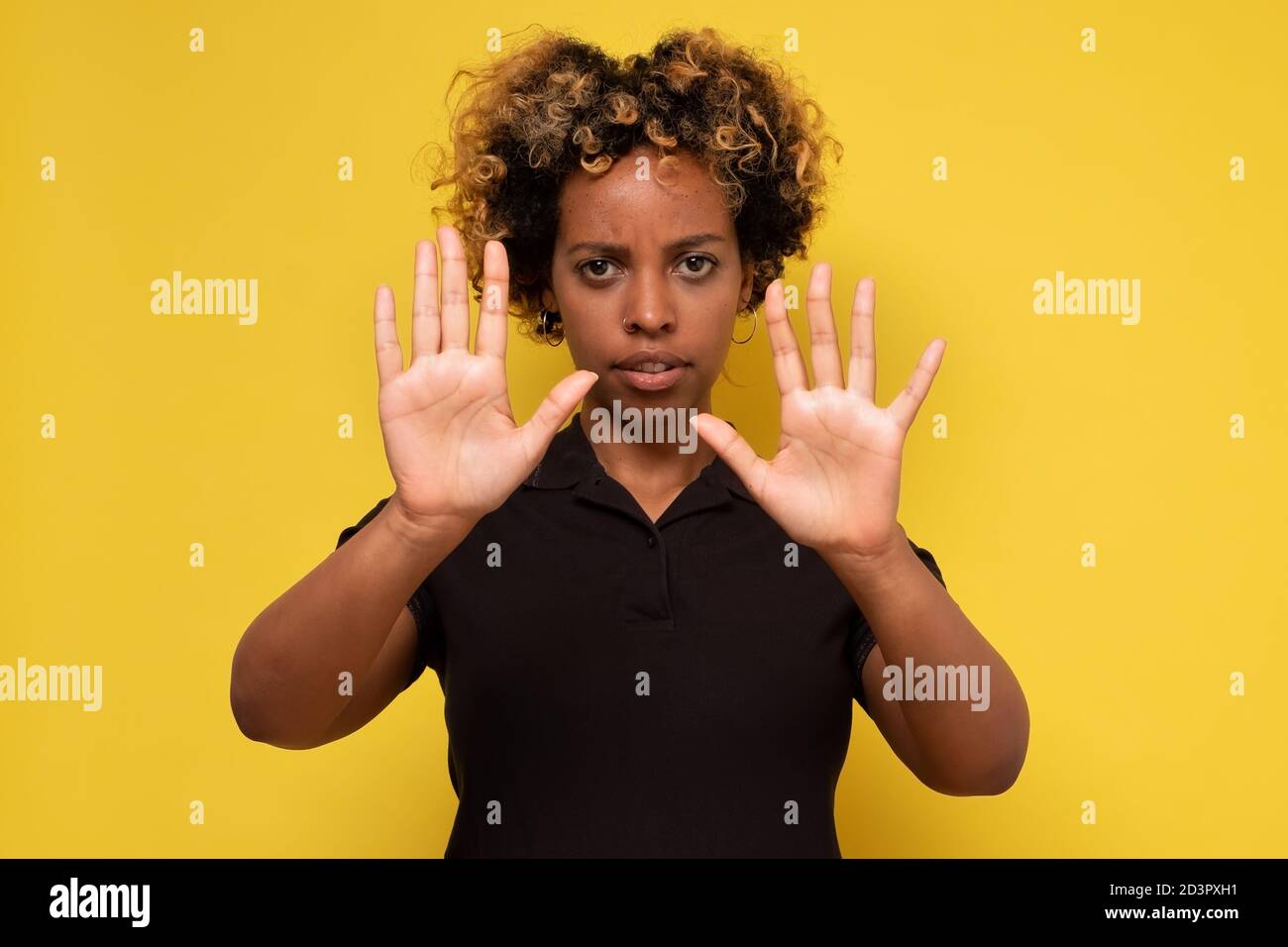 Young african woman makes a gesture stop, on a yellow background Stock Photo