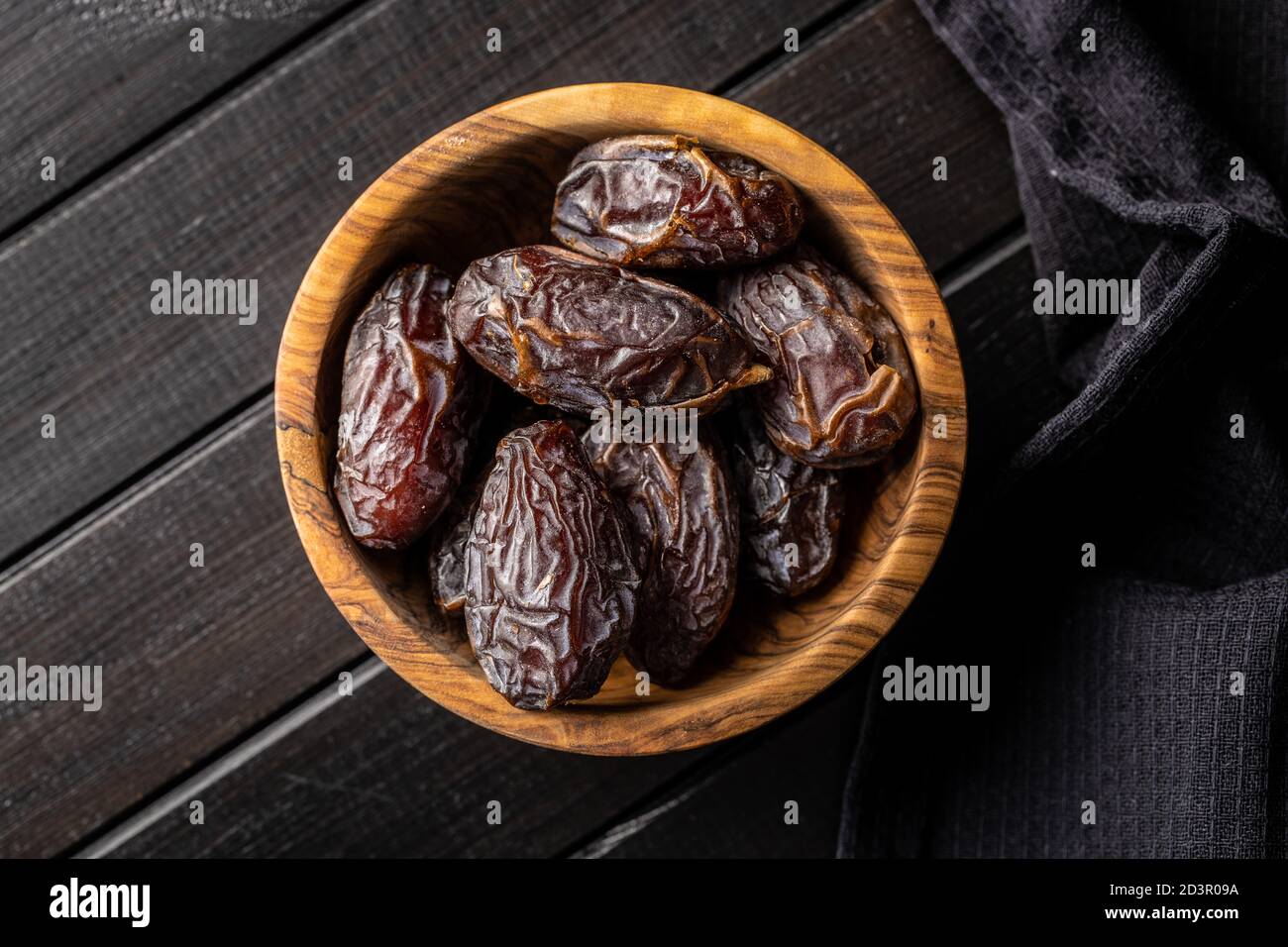 Dried dates fruit in wooden bowl on black wooden table. Top view Stock ...
