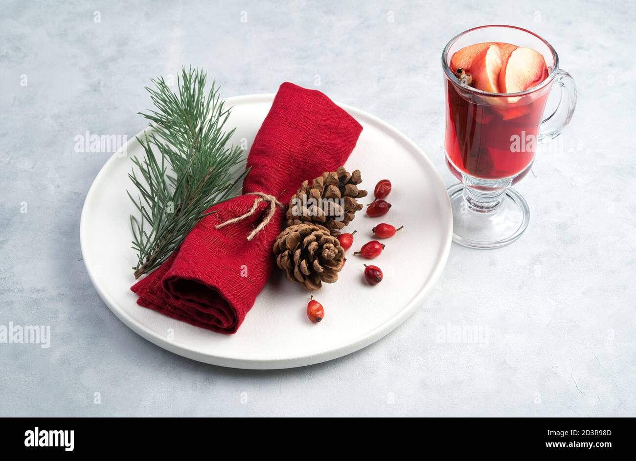 Christmas composition with a glass of mulled wine and a beautifully decorated plate with spruce branches and a red napkin. Stock Photo