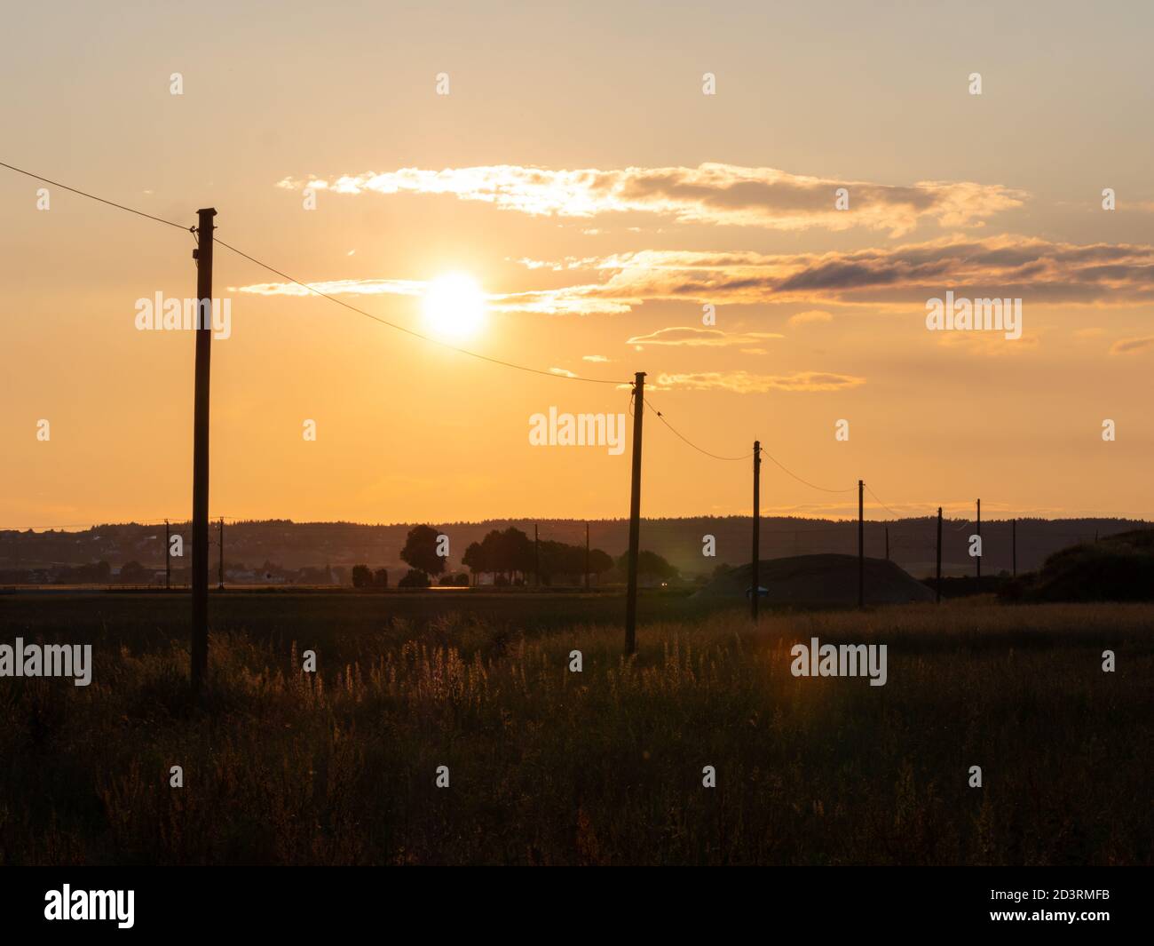 Sunset with the silhouette of high voltahe power posts. Beautiful natural landscape in the summer time Stock Photo