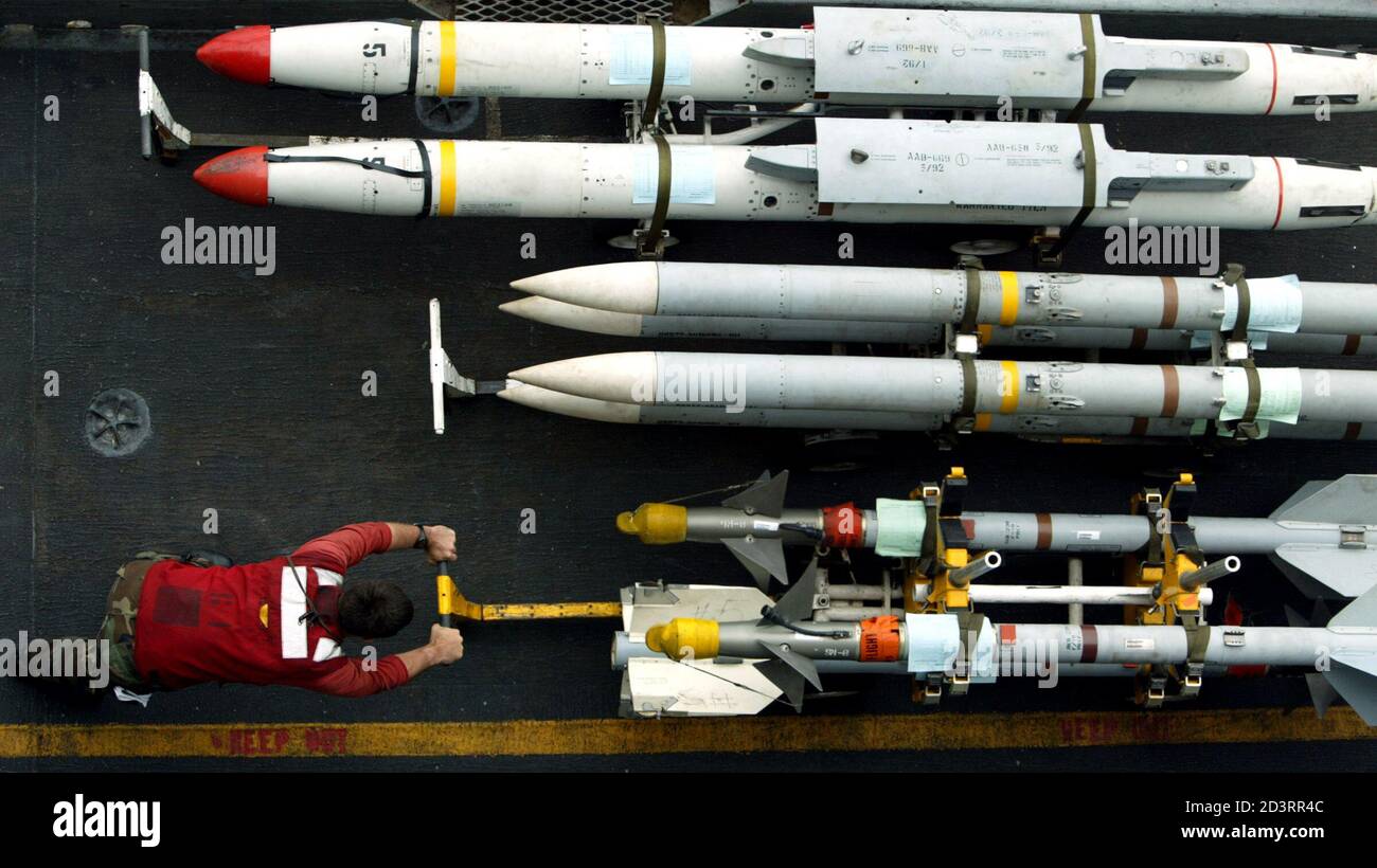 An aviation ordinanceman wheels AIM-9 sidewinder air-to-air missiles into place alongside AIM-120 AMRAAM air-to-air intercept missiles (C) and AGM-88 HARM air-to-ground missiles on the flight deck of the USS Kitty Hawk in the northern Persian Gulf March 10, 2003. U.S. and British navies are more worried about al Qaeda strikes on ships in the event of war with Iraq than anything Saddam Hussein could throw at them, the deputy allied sea commander said on Monday. REUTERS/Paul Hanna  PH/WS Stock Photo