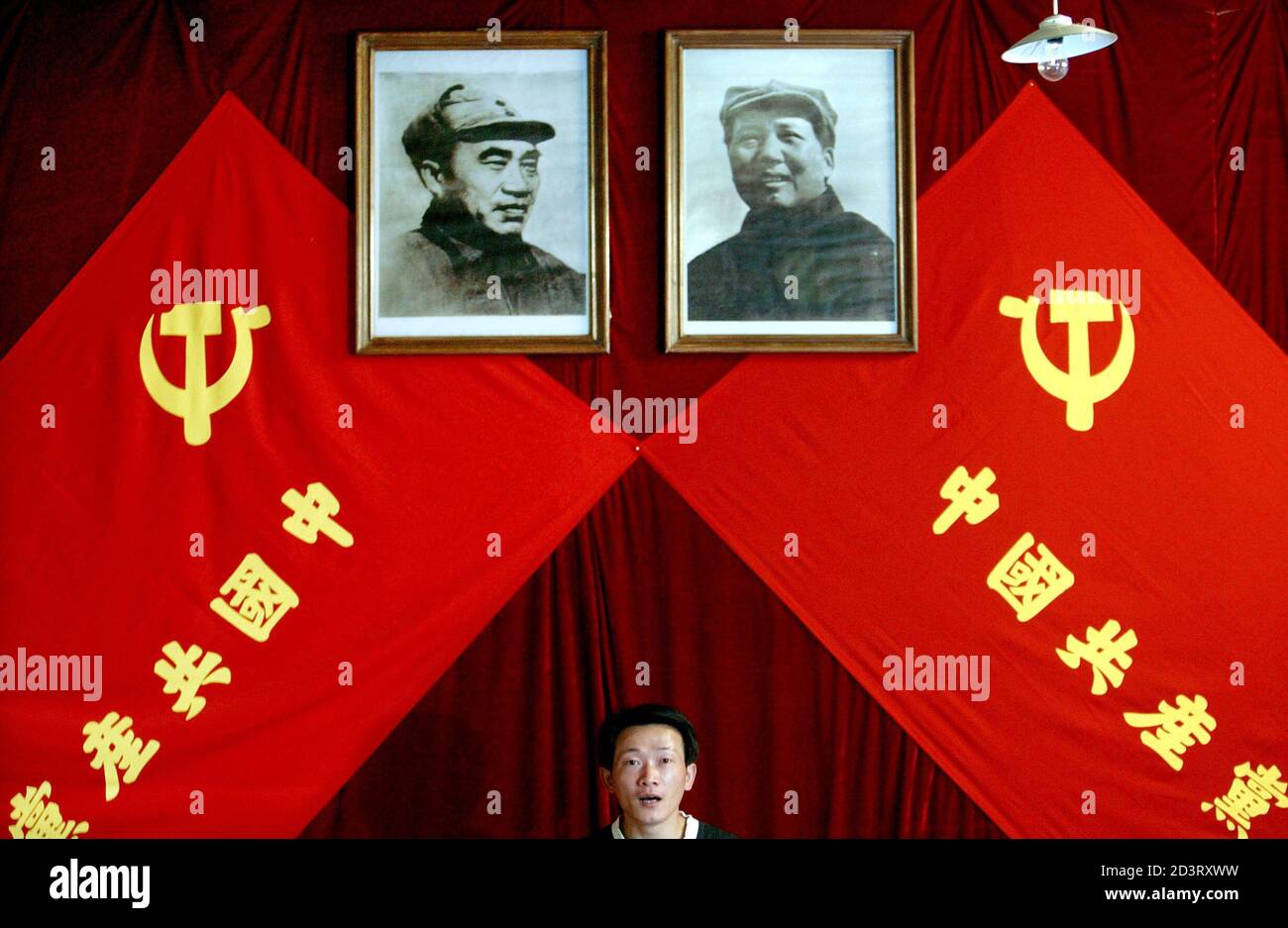 A Chinese man stands underneath portraits of the late chairman Mao Zedong (R) and the late general Zhu De at an exhibition in Beijing June 15, 2004. The exhibition is aimed to promote China's Communist Party which celebrates its 83rd anniversary on July 1. The Chinese characters on the flags read: "China's Communist Party". REUTERS/Guang Niu ASW/LA Stock Photo