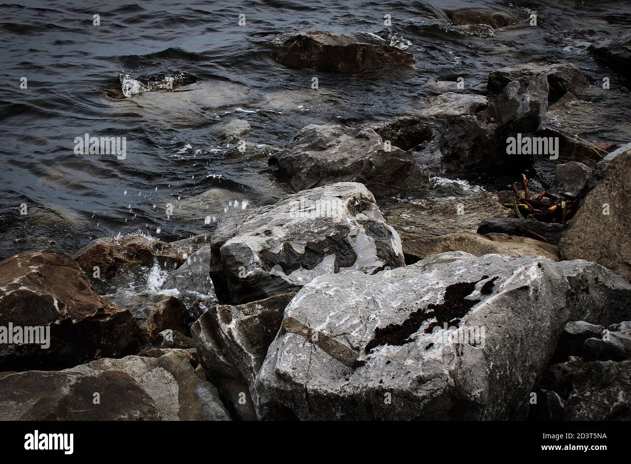 calm dark water gently slips over rocks Stock Photo Alamy