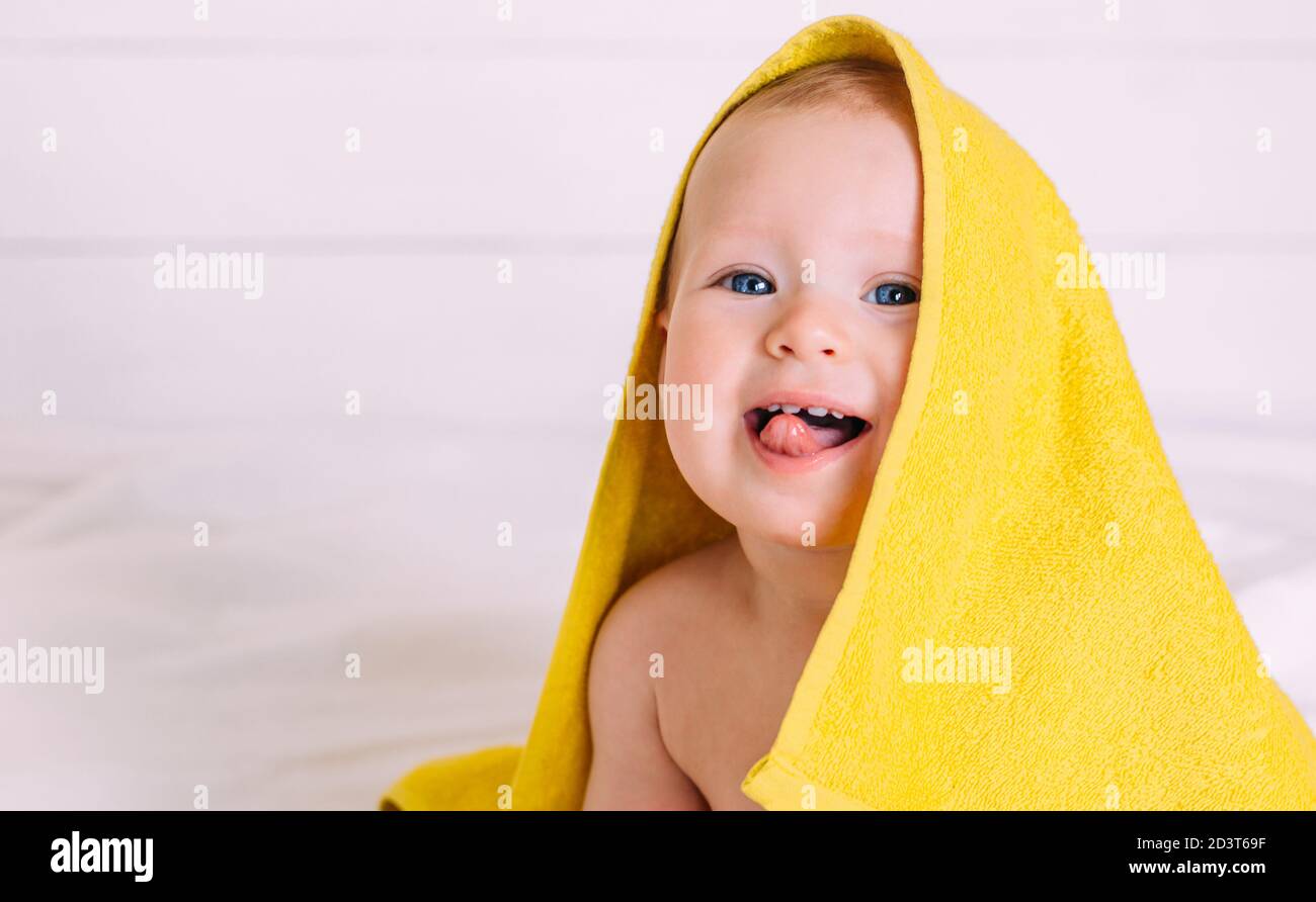 A cute baby with blue eyes wrapped in a towel as the hood looks into